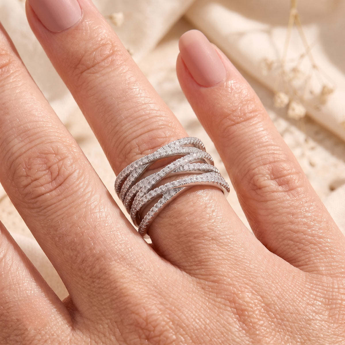 Sterling silver crossover ring with simulated diamonds shown on a model's hand.