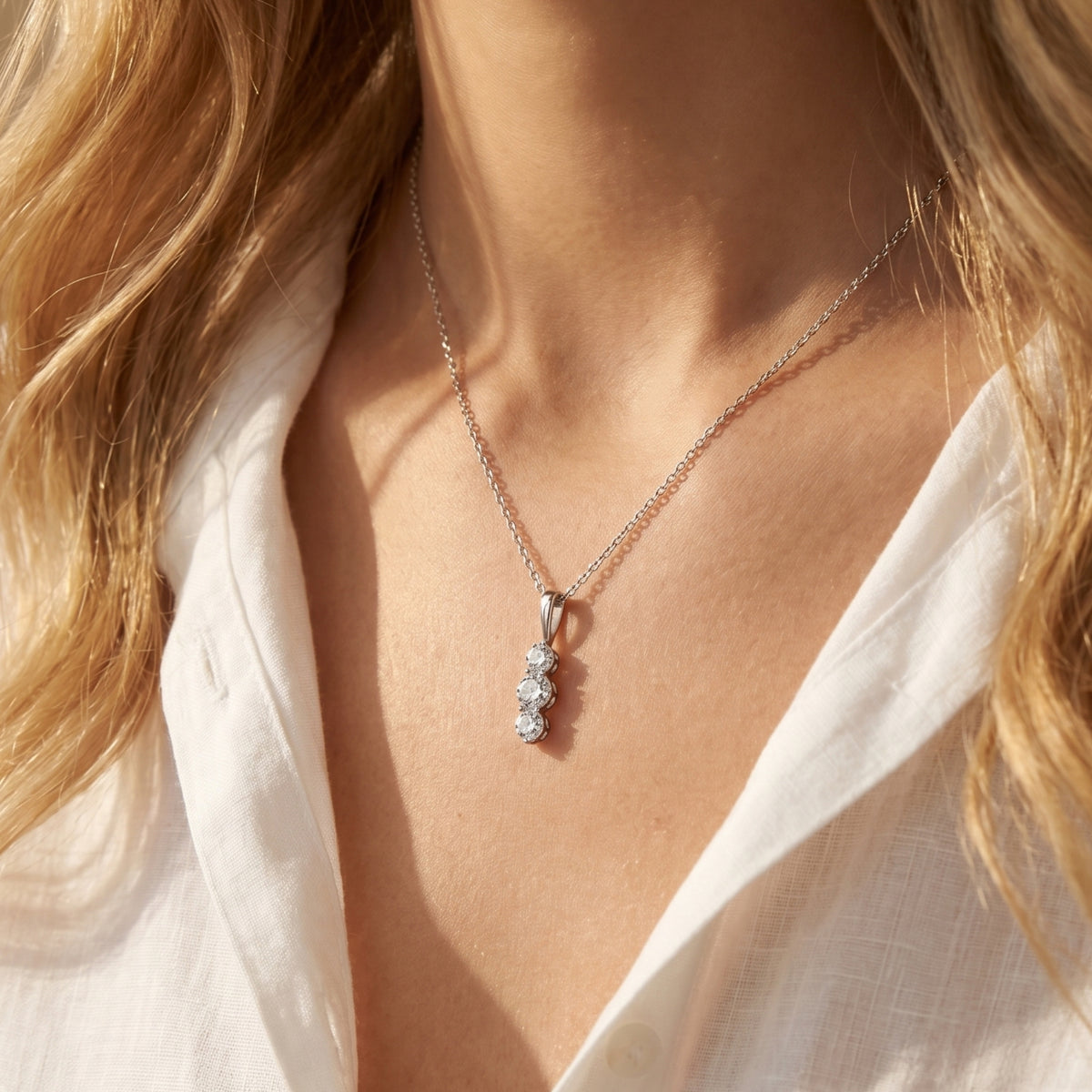 Woman wearing the Larisa moissanite necklace with three vertical round stones.
