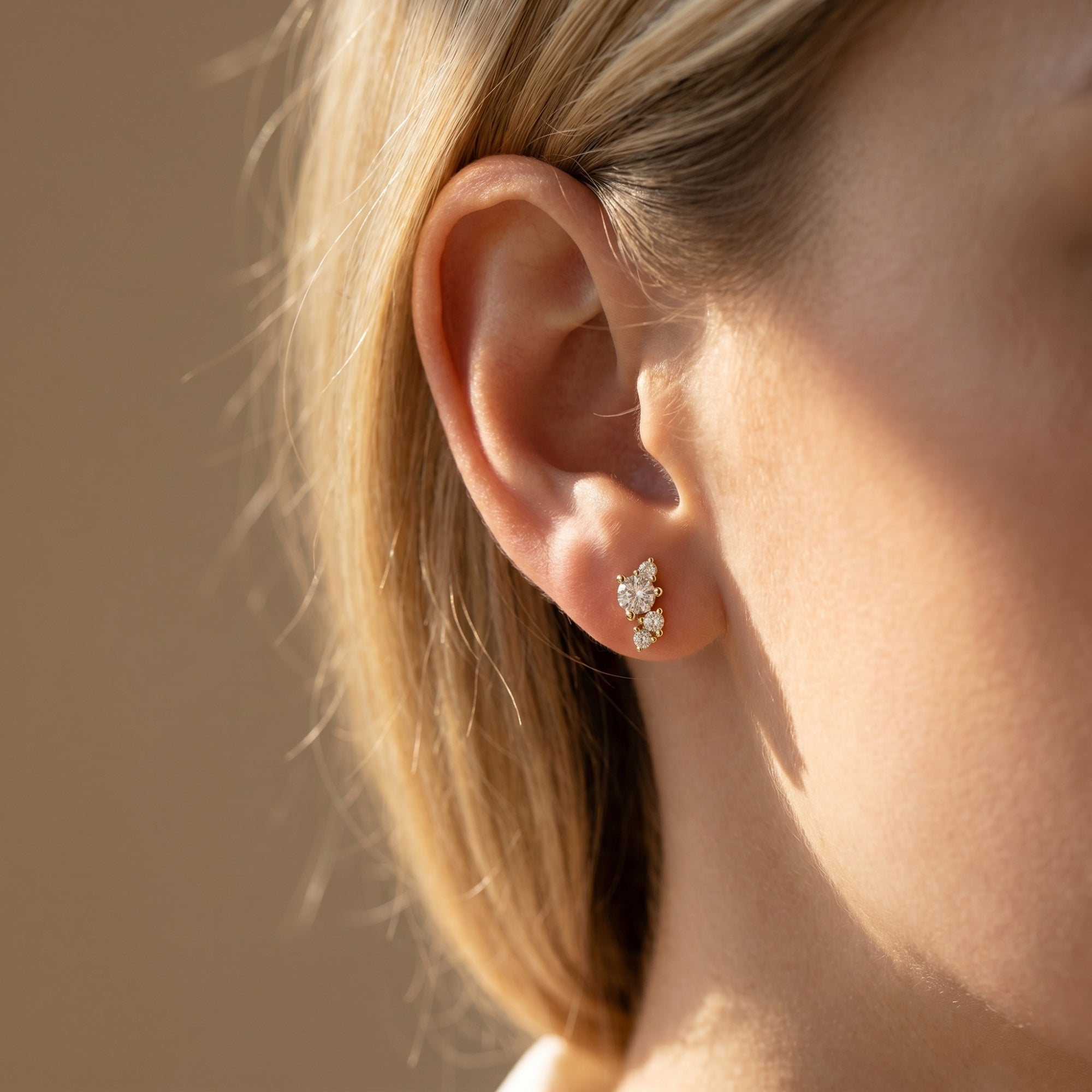 Side view of a gold moissanite cluster earring worn on a model's ear.