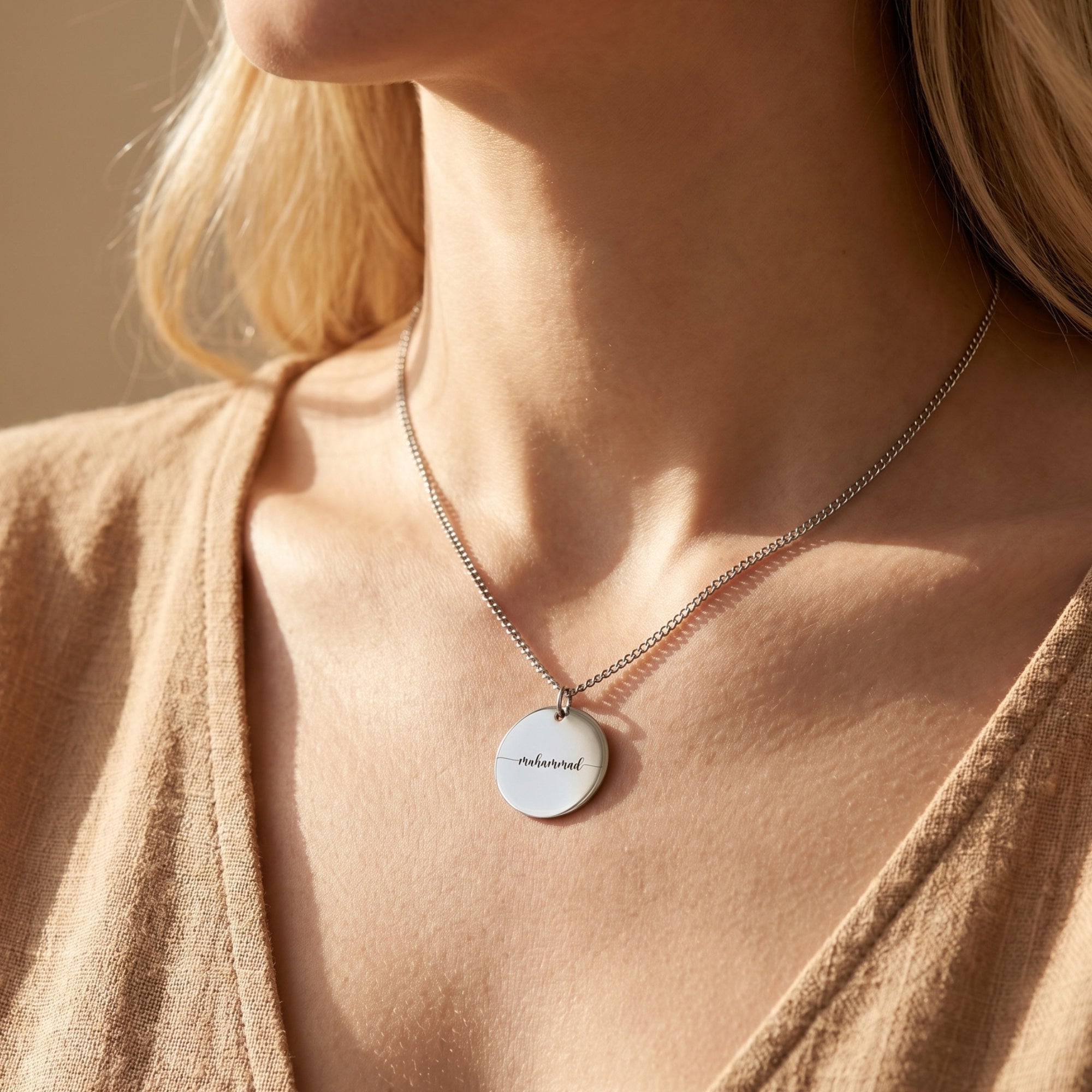 Silver Eloise stainless steel engraved disc necklace worn by a woman.