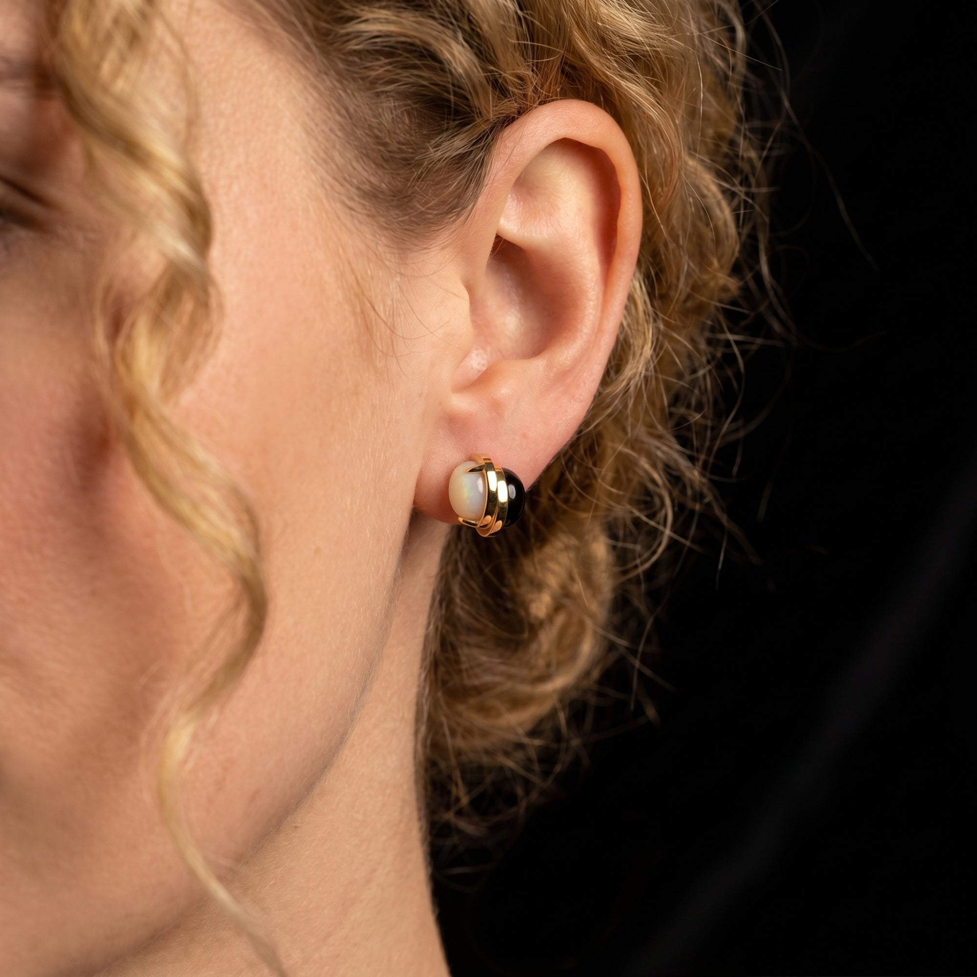 Side view of a model wearing an 18K gold plated Ravenna earring with a round white chalcedony stone.