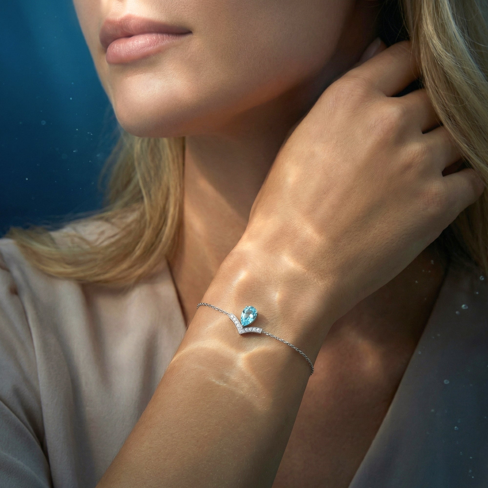 Close-up of a pear-cut natural aquamarine Pt950 platinum bracelet with diamond accents on a model's wrist.