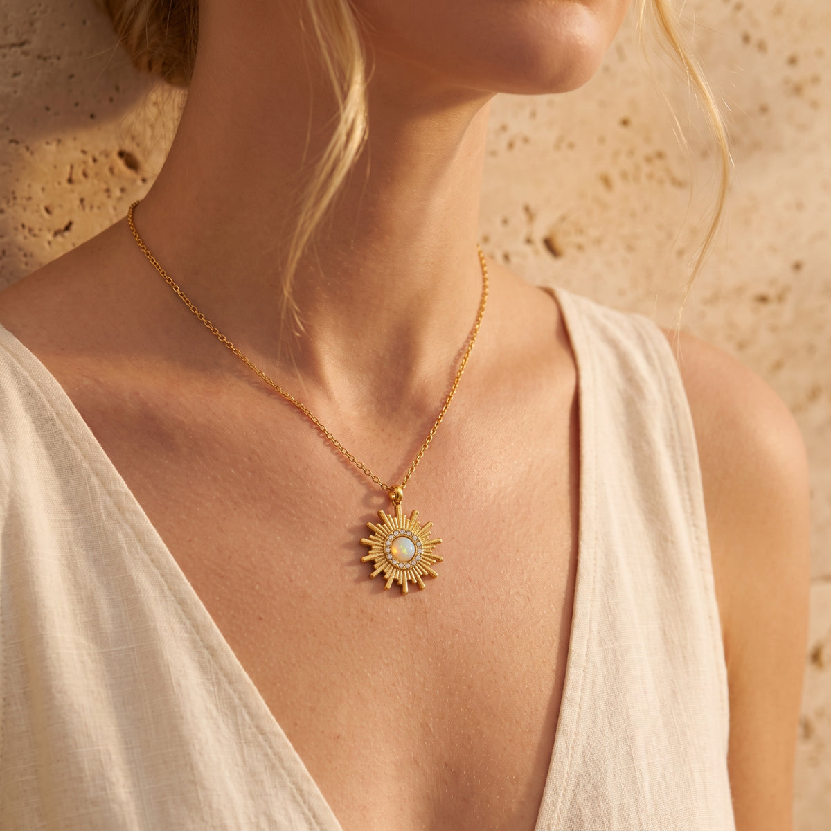 Wider view of a model wearing the gold-tone sunburst opal pendant necklace over a white top.
