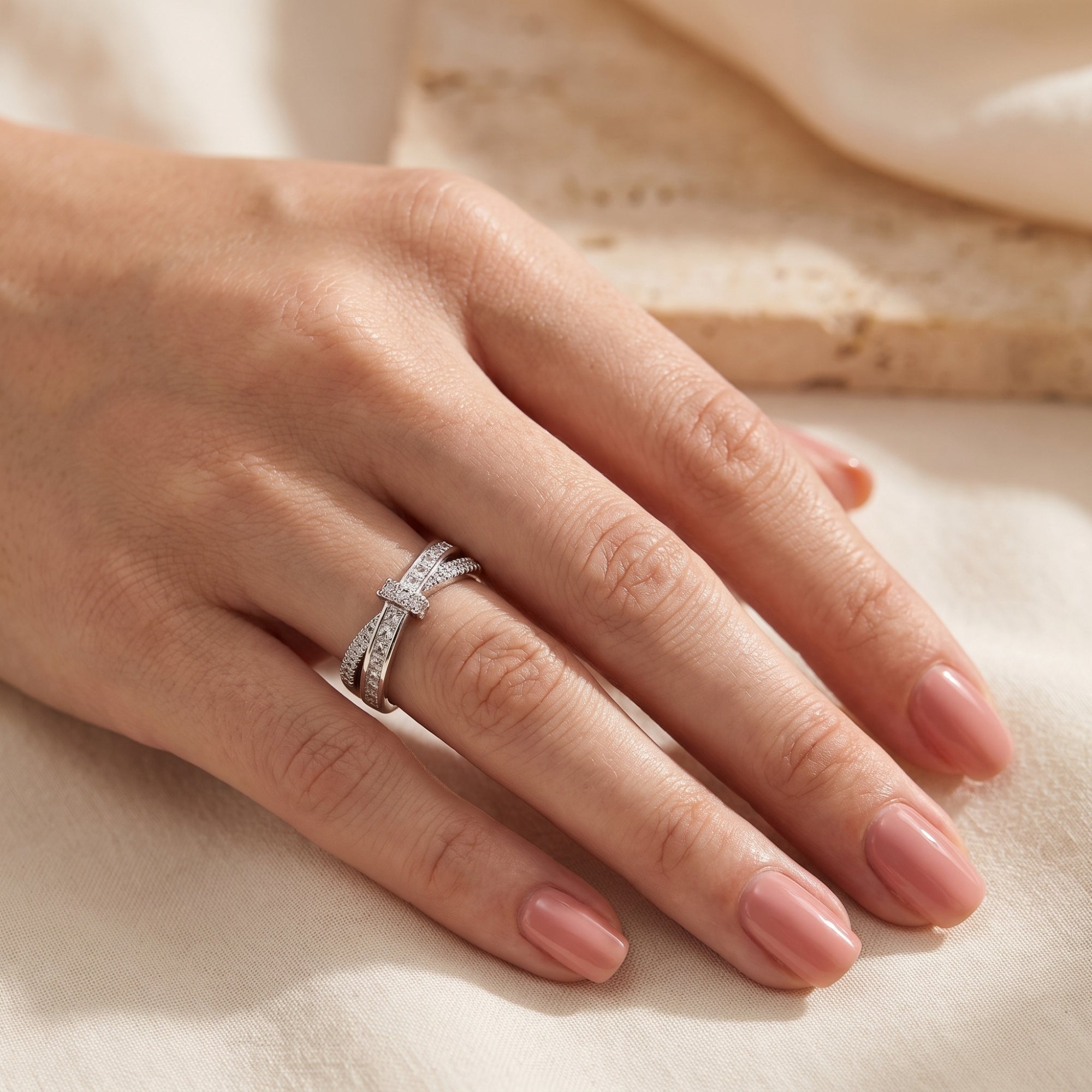 Side view of the Charlotte silver ribbon promise ring with sparkling CZ stones worn on a woman's finger.