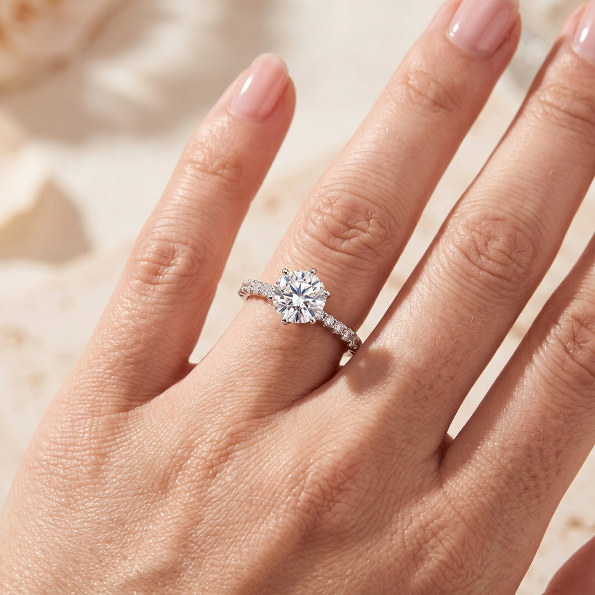 Close-up shot of the silver six-prong solitaire ring worn on a hand, highlighting the round center stone.