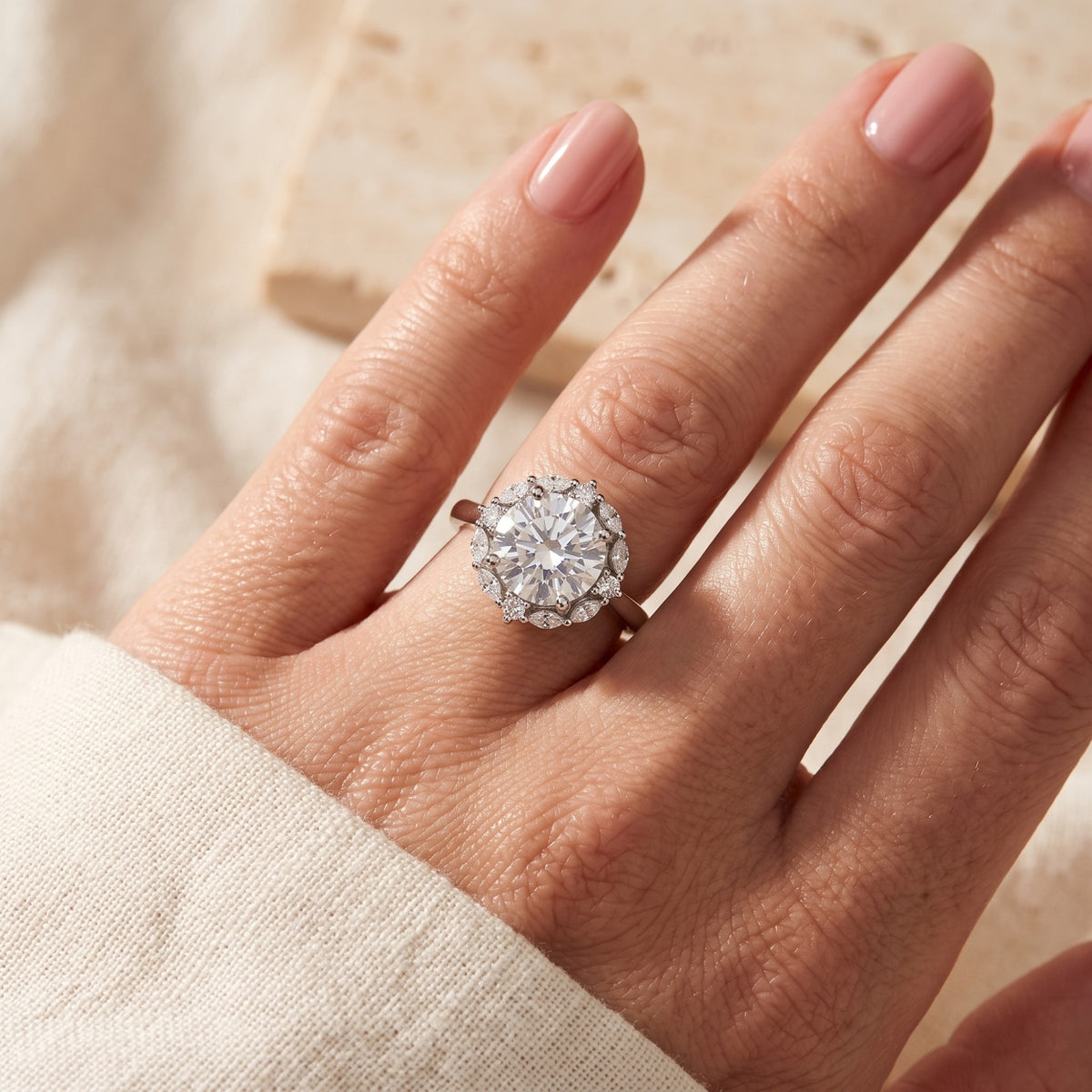 Close-up of a hand wearing the silver Sunburst Halo Ring with a round center stone and detailed halo.