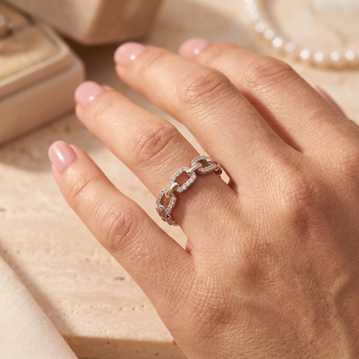 Silver pavé link ring on a finger showing the interlocking chain motif.