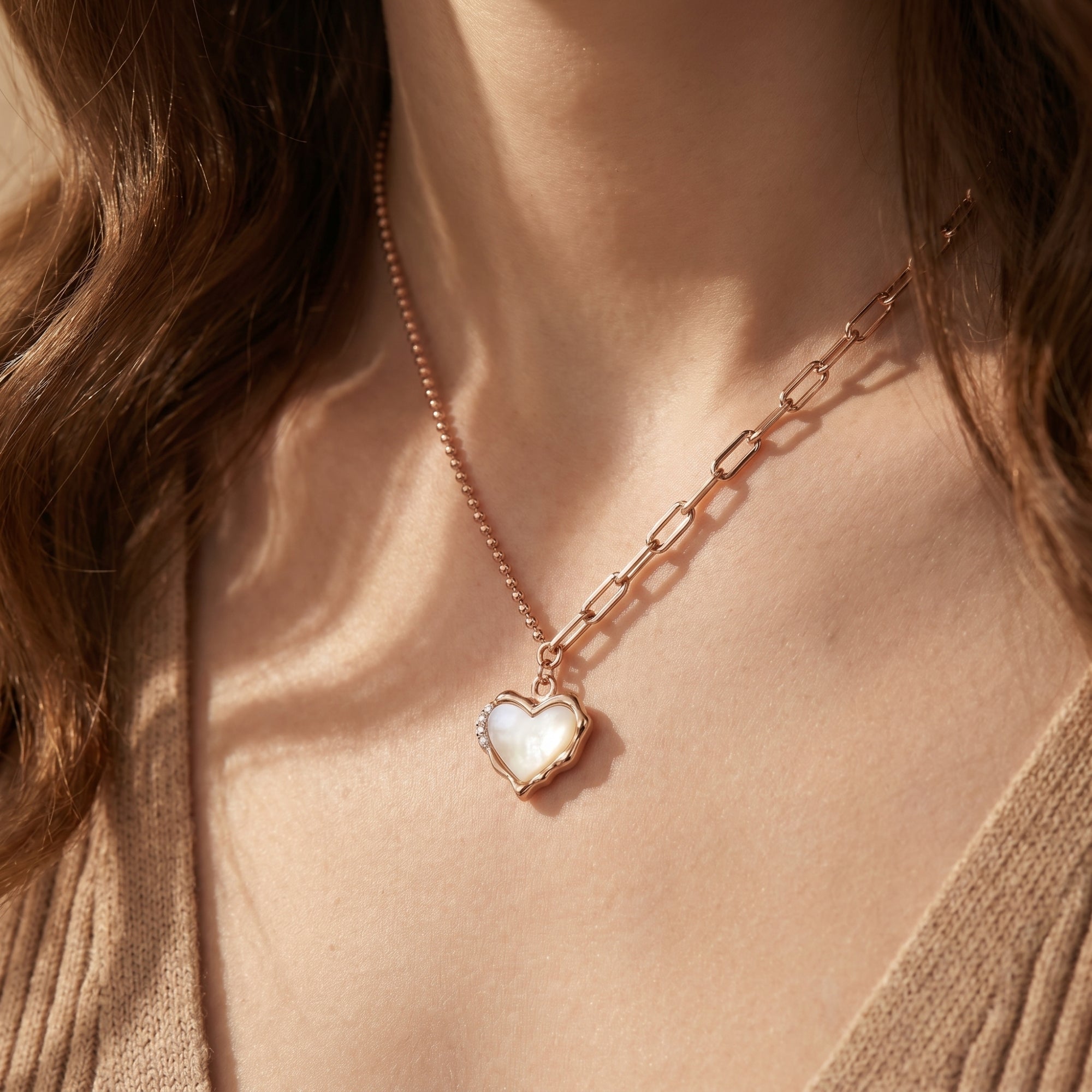 Rose gold heart necklace with white opal pendant worn by a model, featuring a unique mixed chain.