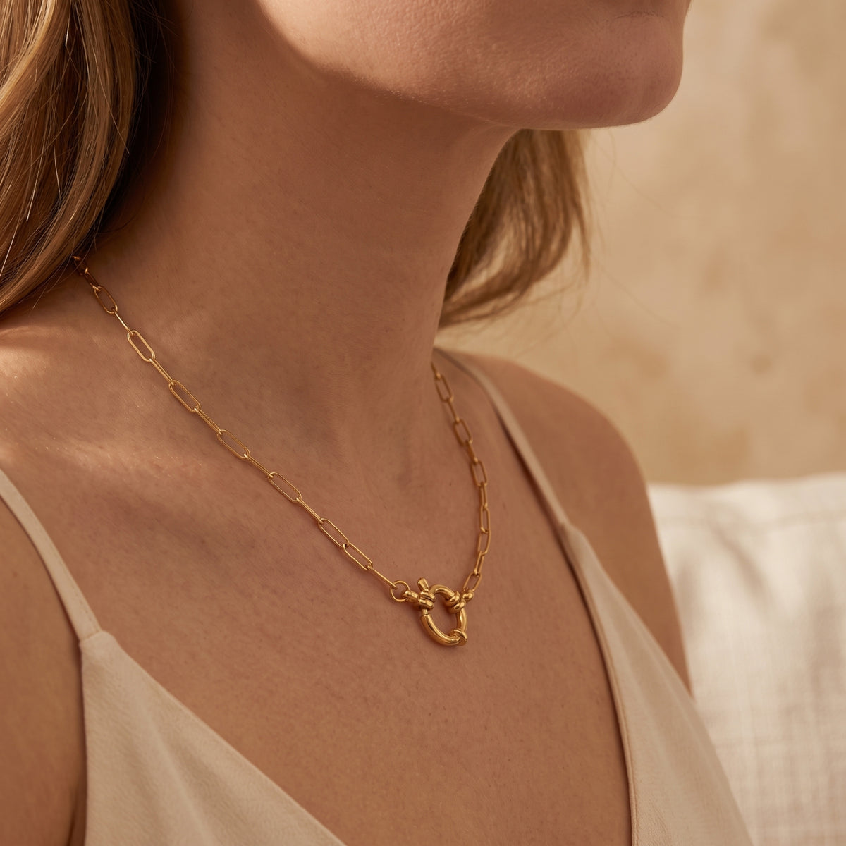 Side-profile view of a model wearing the gold-tone sailor lock paperclip chain against her neckline.