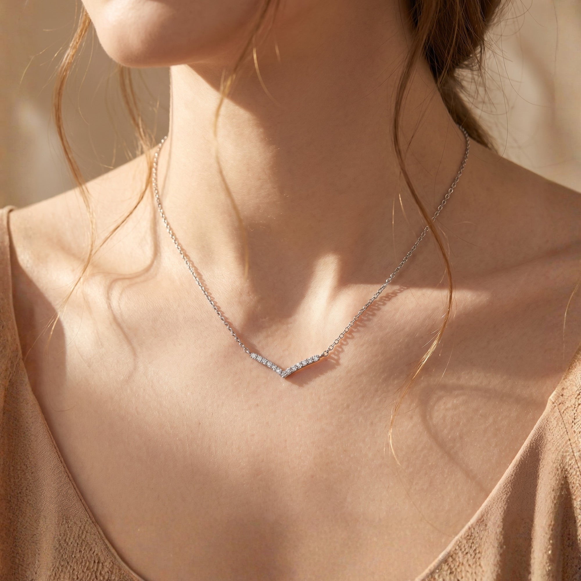 Silver moissanite chevron necklace styled on a woman's neck.