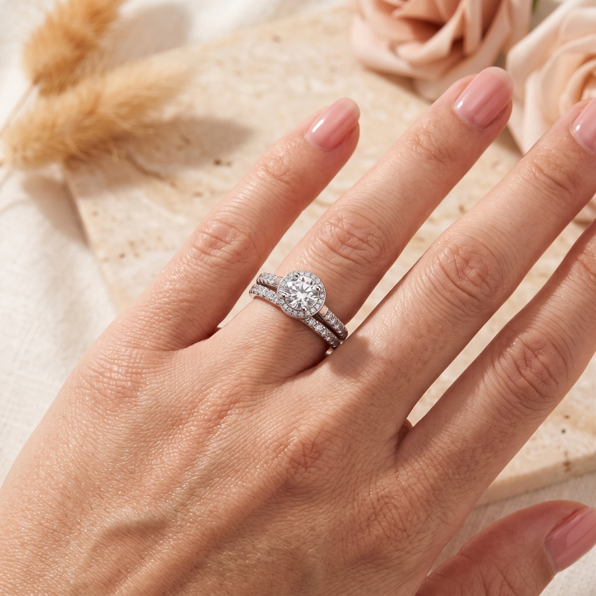 Top view of the Myrella silver halo ring set with round simulated diamonds on a model's hand.