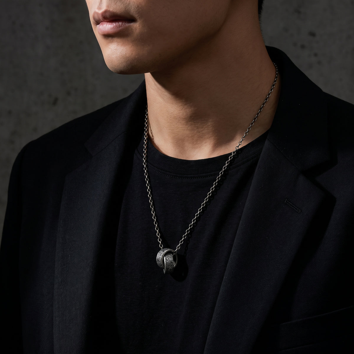 Man wearing the silver dual-ring pendant necklace styled with a black T-shirt and blazer.