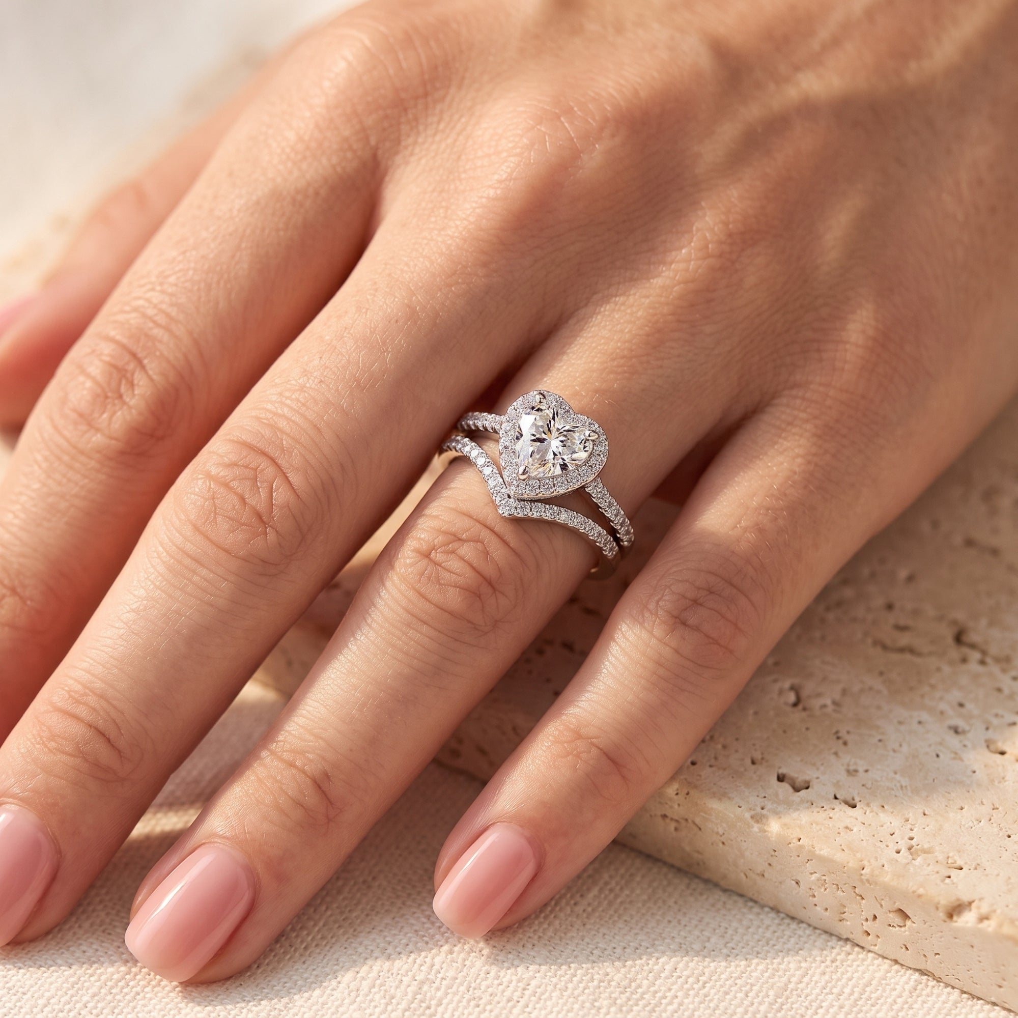 Silver heart halo ring and chevron band set worn on a woman's finger.