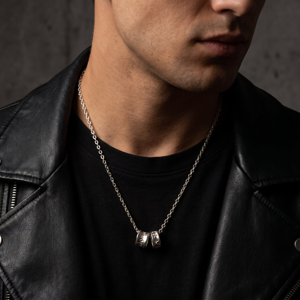 Man wearing the silver dual-cylinder pendant necklace over a black T-shirt and leather jacket.