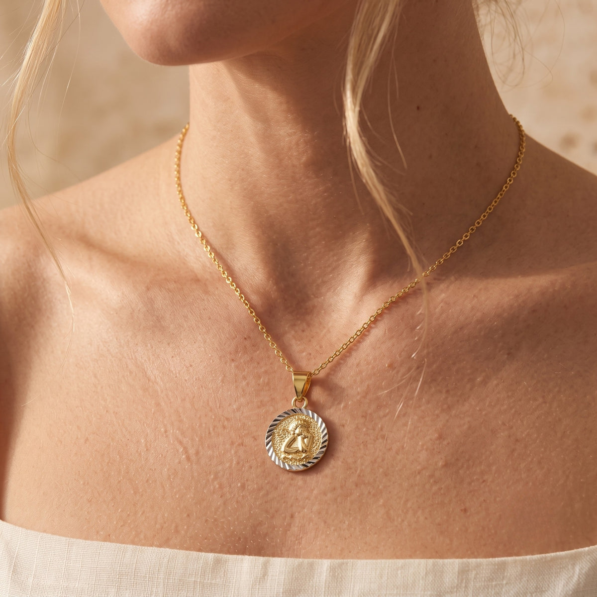 Frontal close-up of a model wearing the two-tone cherub pendant necklace at chest level.