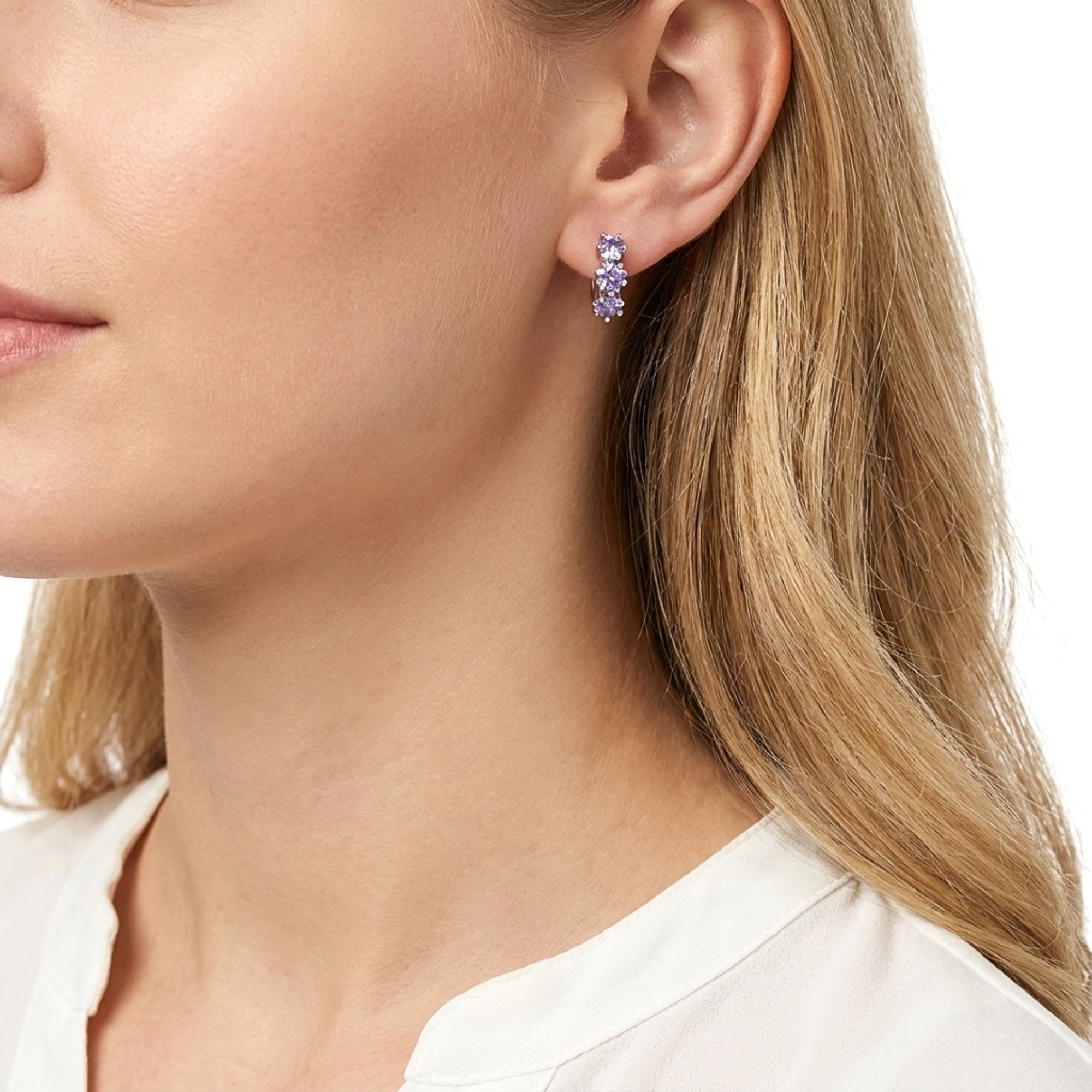 Side profile of a woman wearing the Asteria S925 sterling silver huggies with purple star-cut stones.