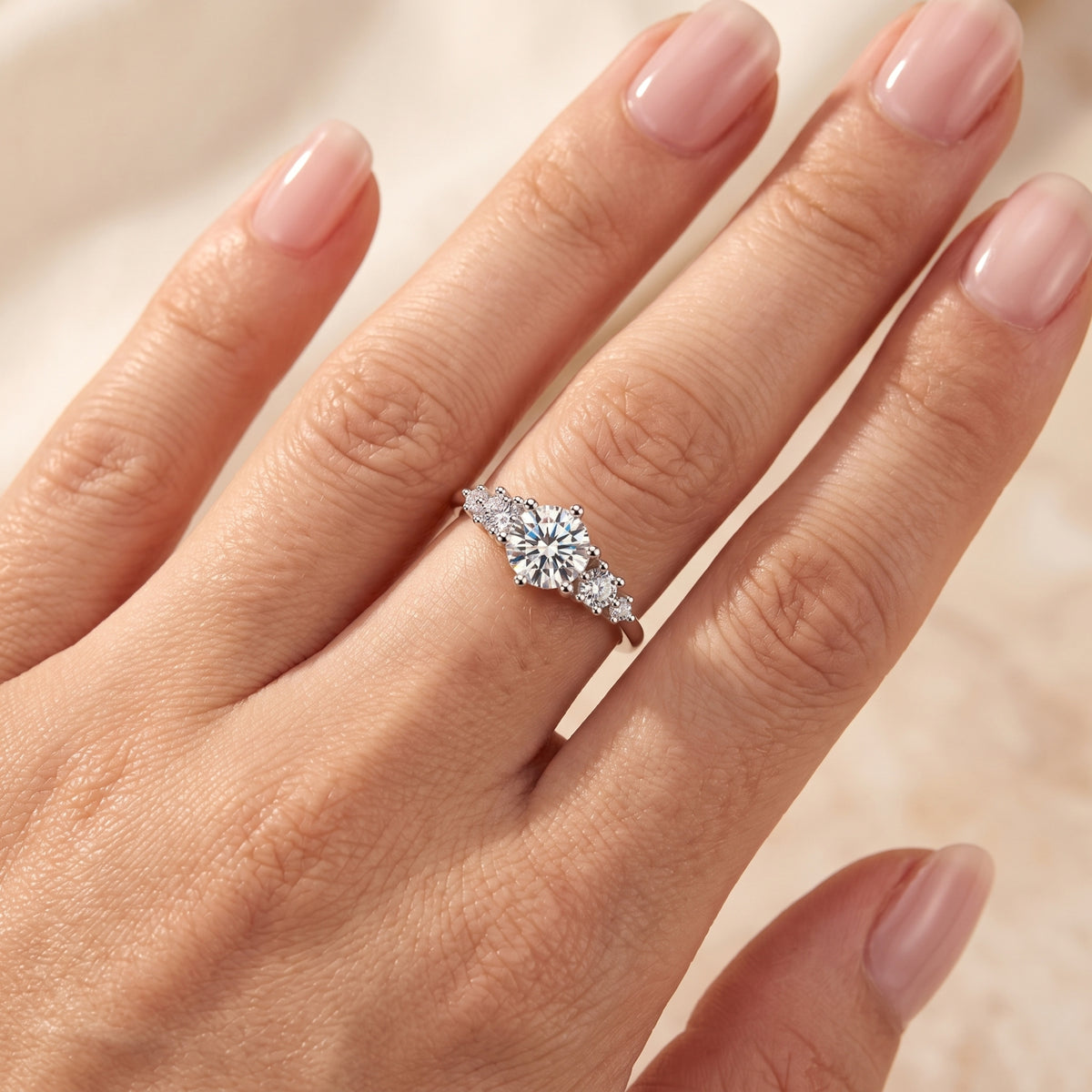 Top-down view of the silver ring with a round center stone and clustered accents worn on a hand