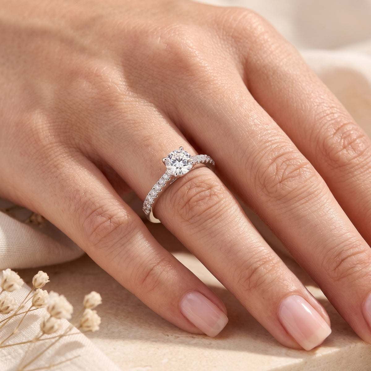 Round simulated diamond sterling silver ring shown on a finger.