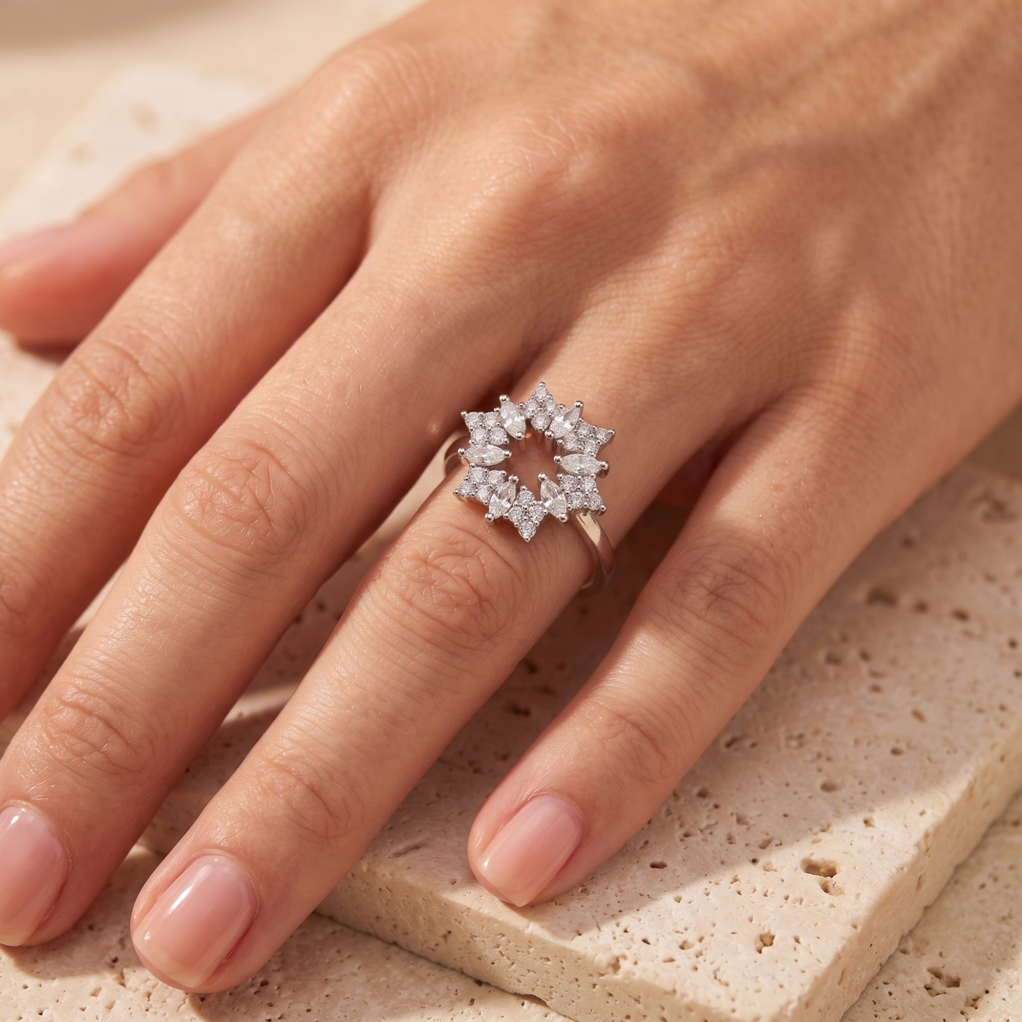 Top-down view of the Stellaire S925 sterling silver starburst ring with marquise stones on a finger.