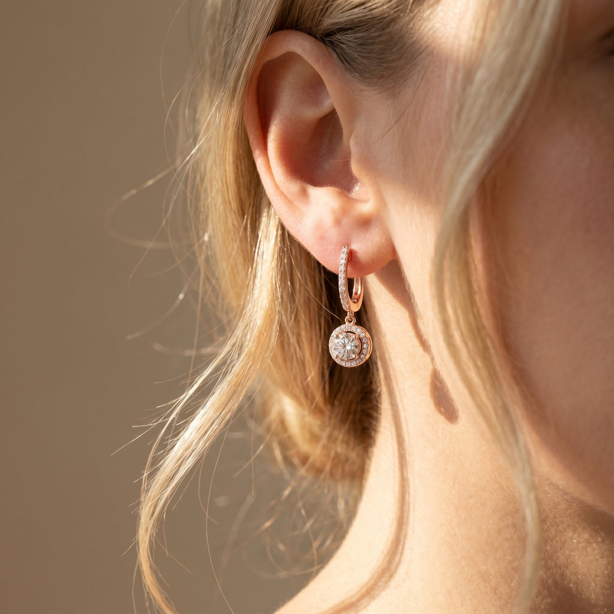 Rose gold round moissanite drop earring worn on a model's ear.