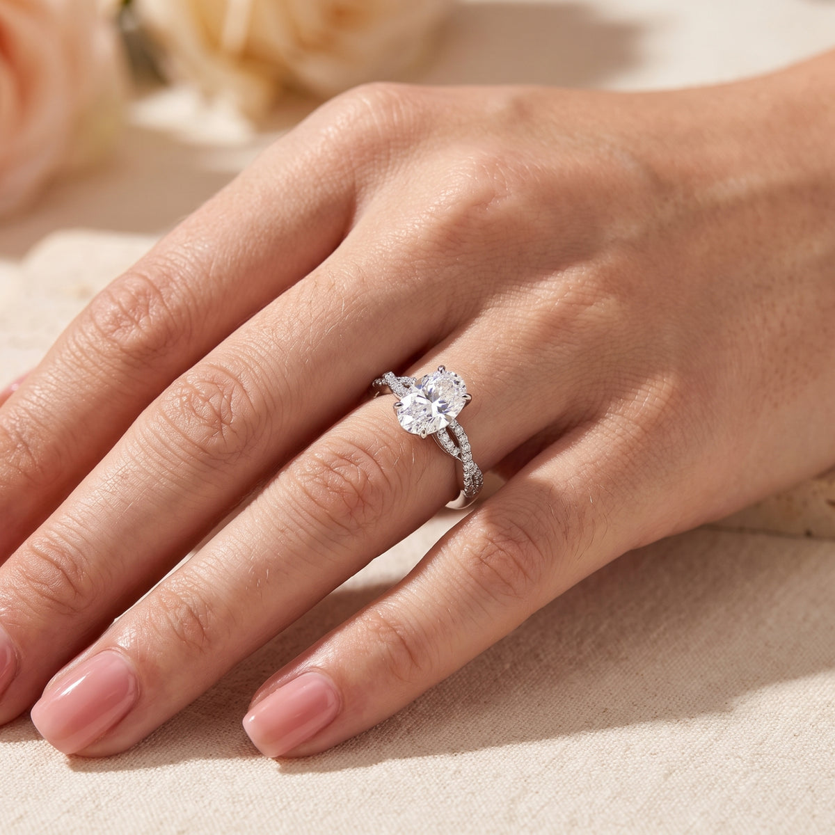 Wider hand view of the oval stone infinity twist ring displayed on a hand against a neutral backdrop.