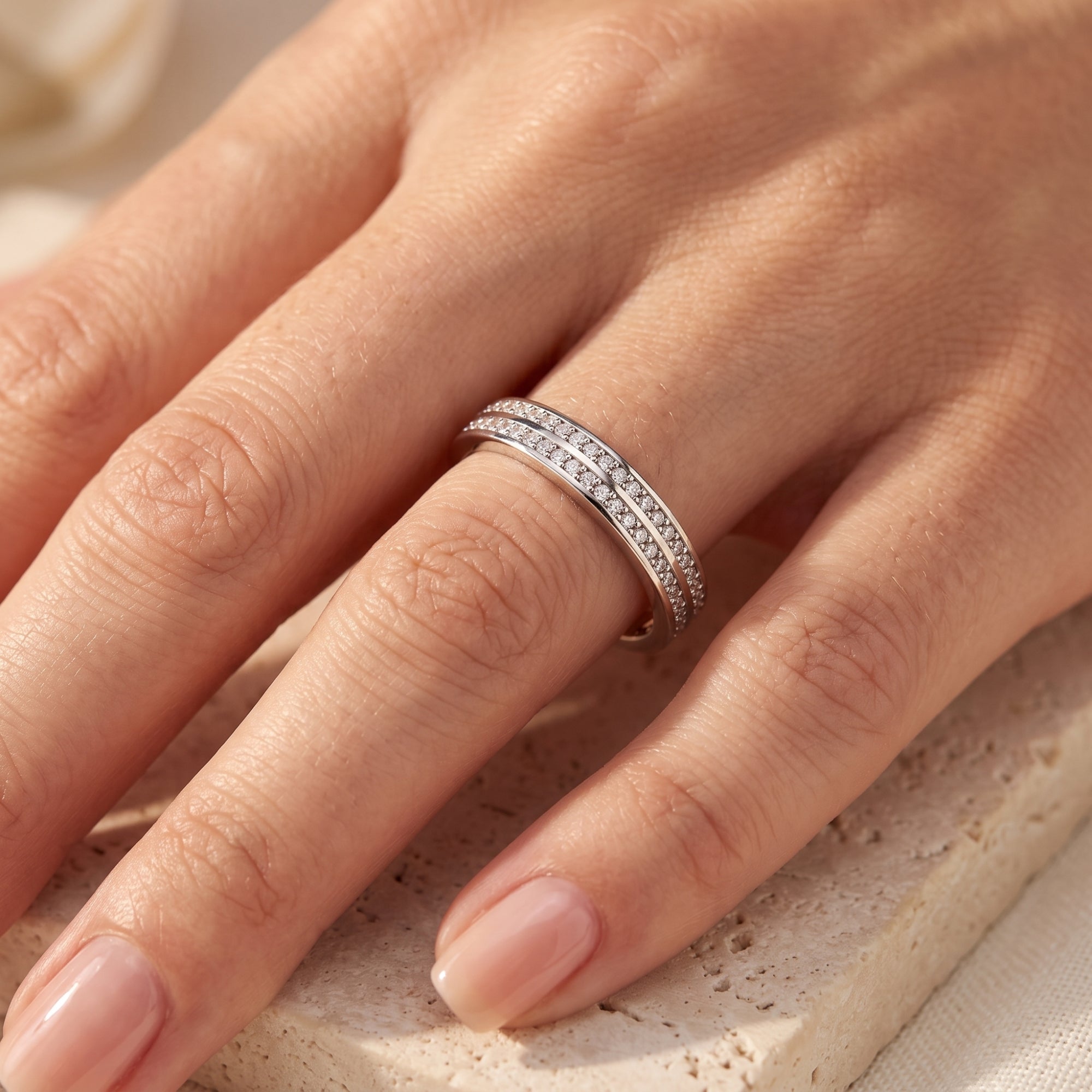 Macro view of the Margaux double-row pavé sterling silver ring with simulated diamonds worn on a finger.