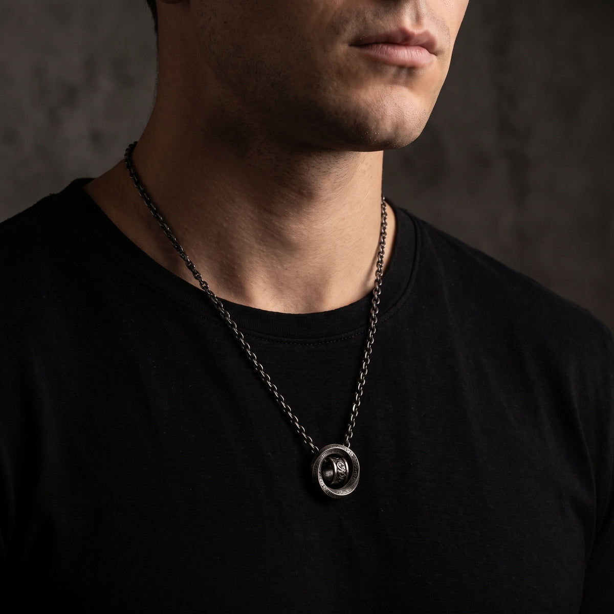 Front torso view of a man wearing the double-ring pendant necklace over a black T-shirt.