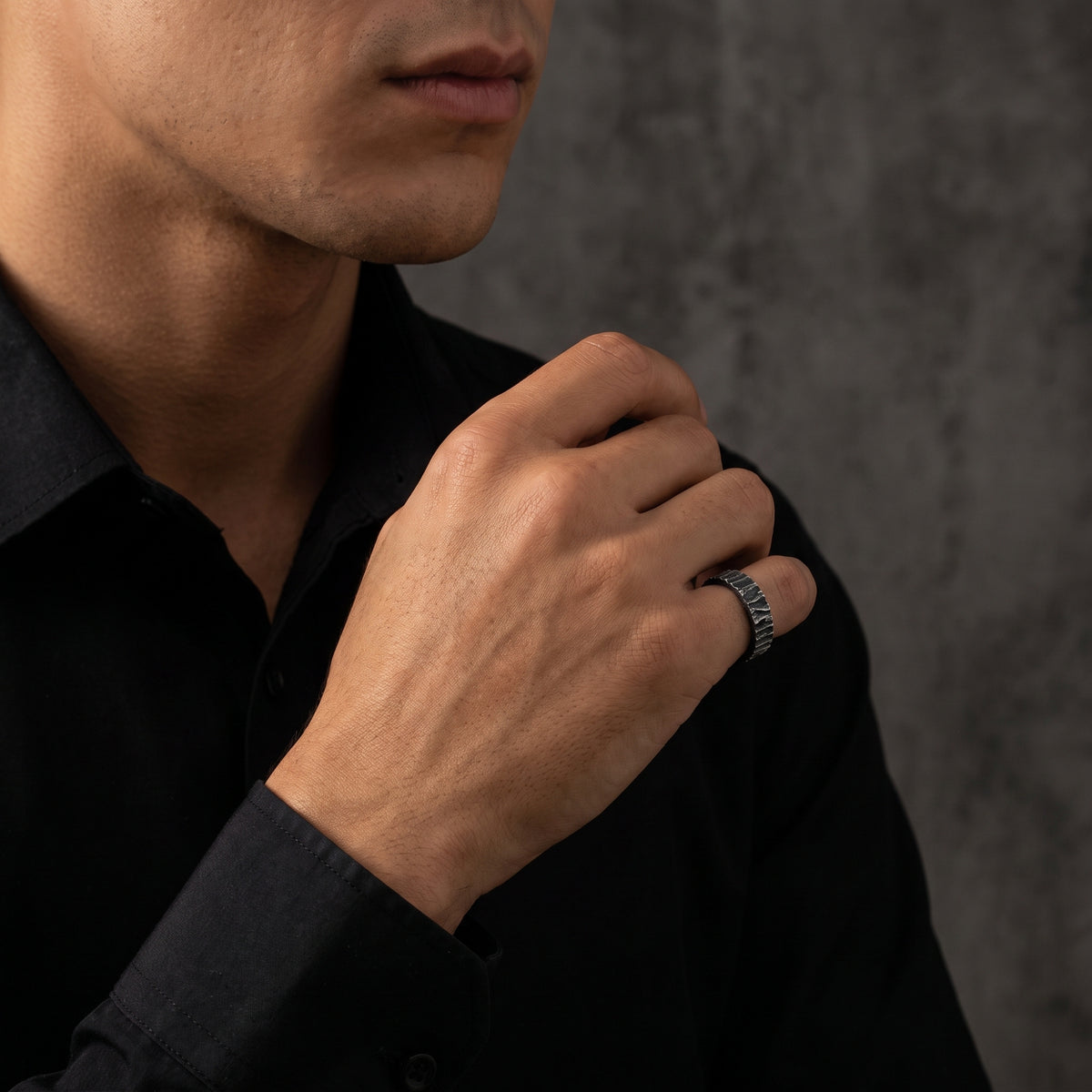 Man wearing the textured silver open band ring on his ring finger over a black shirt.