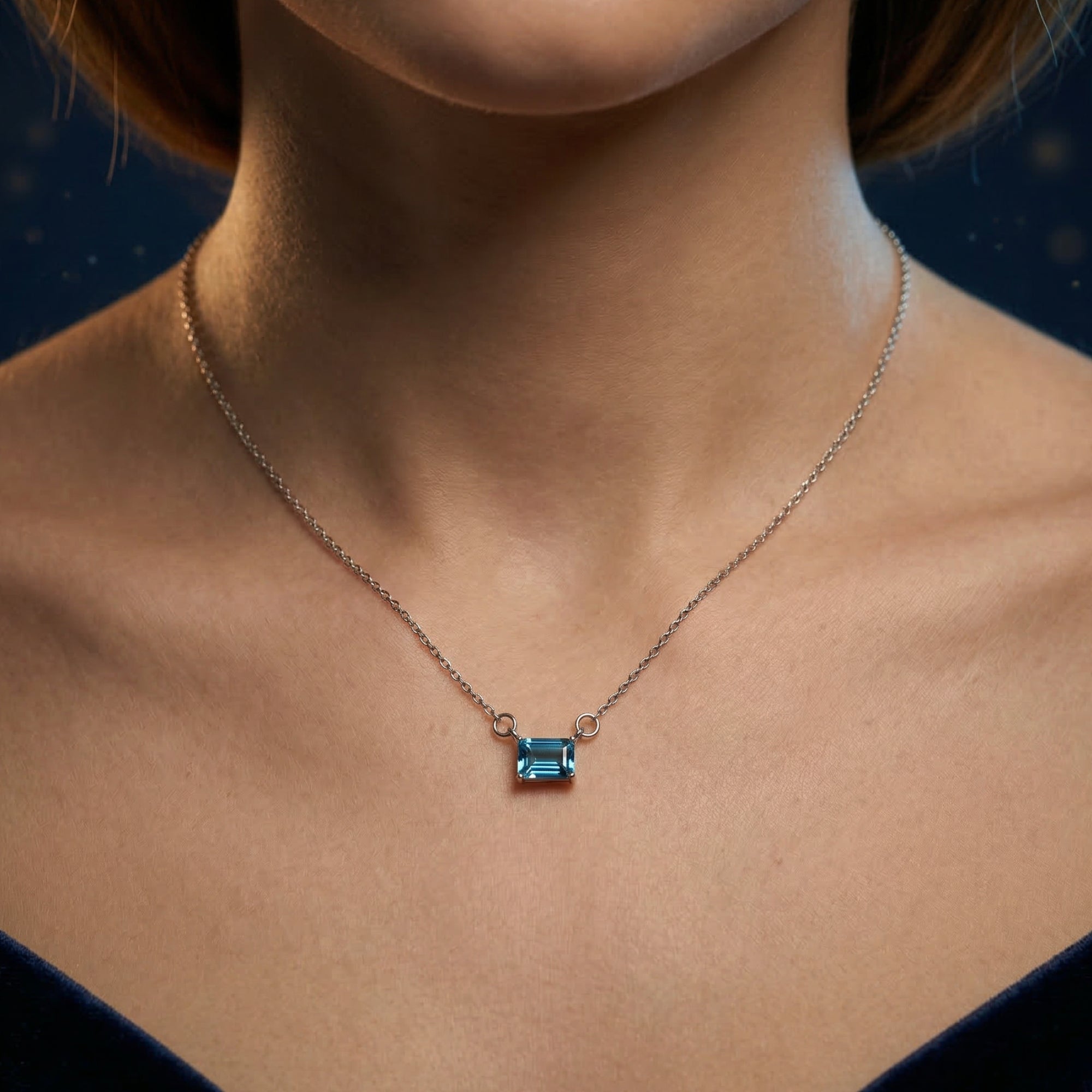 Centered view of the Elyria blue topaz necklace in white gold worn on a model's neck.