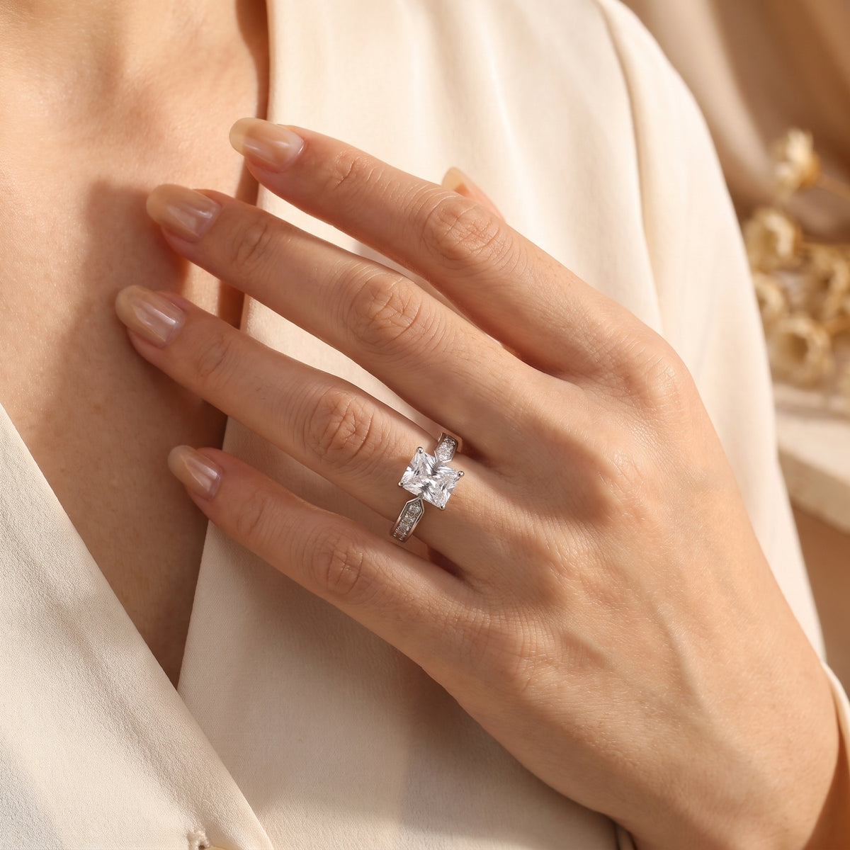Radiant-cut simulated diamond ring in sterling silver styled on a model's hand against a cream blouse.