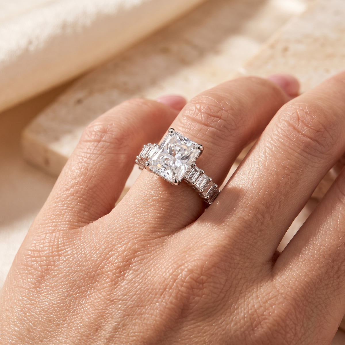 Angled close-up of the radiant cut simulated diamond sterling silver ring worn on a finger.