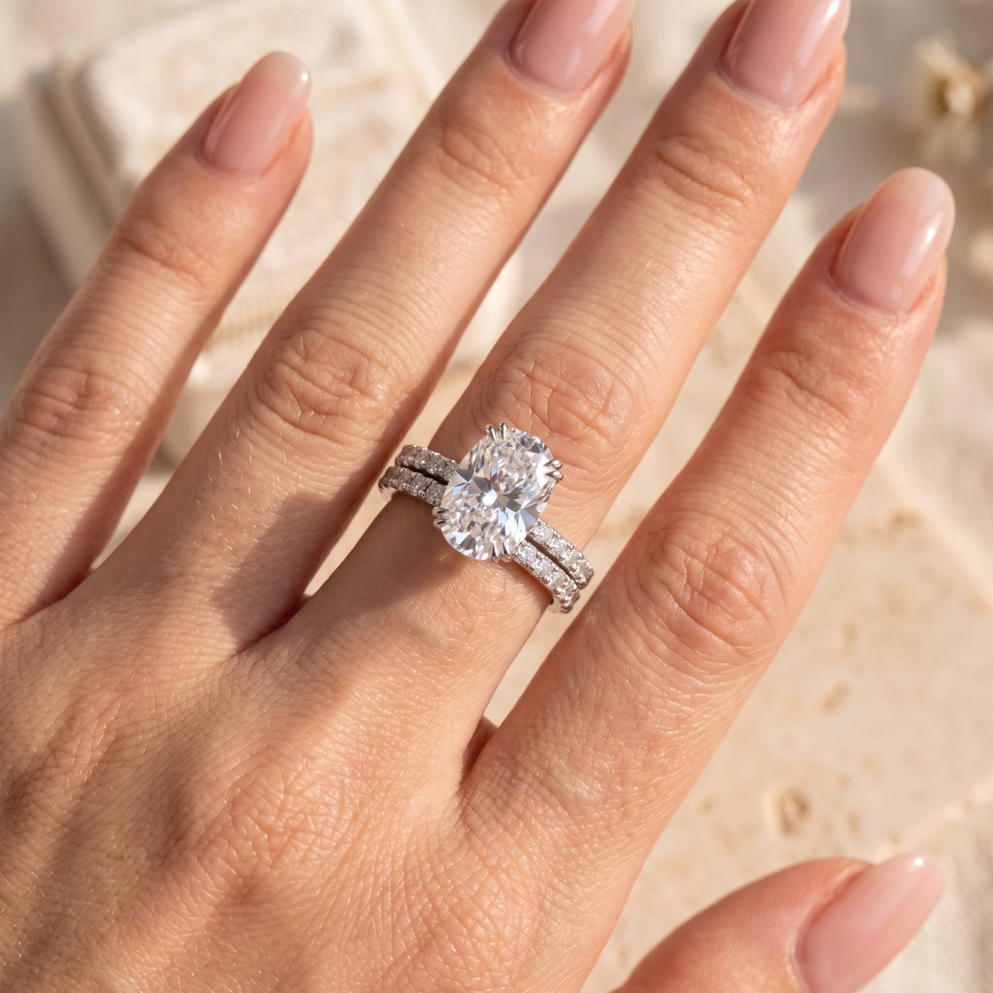 Close-up of a silver oval-cut simulated diamond ring set on a model's finger.