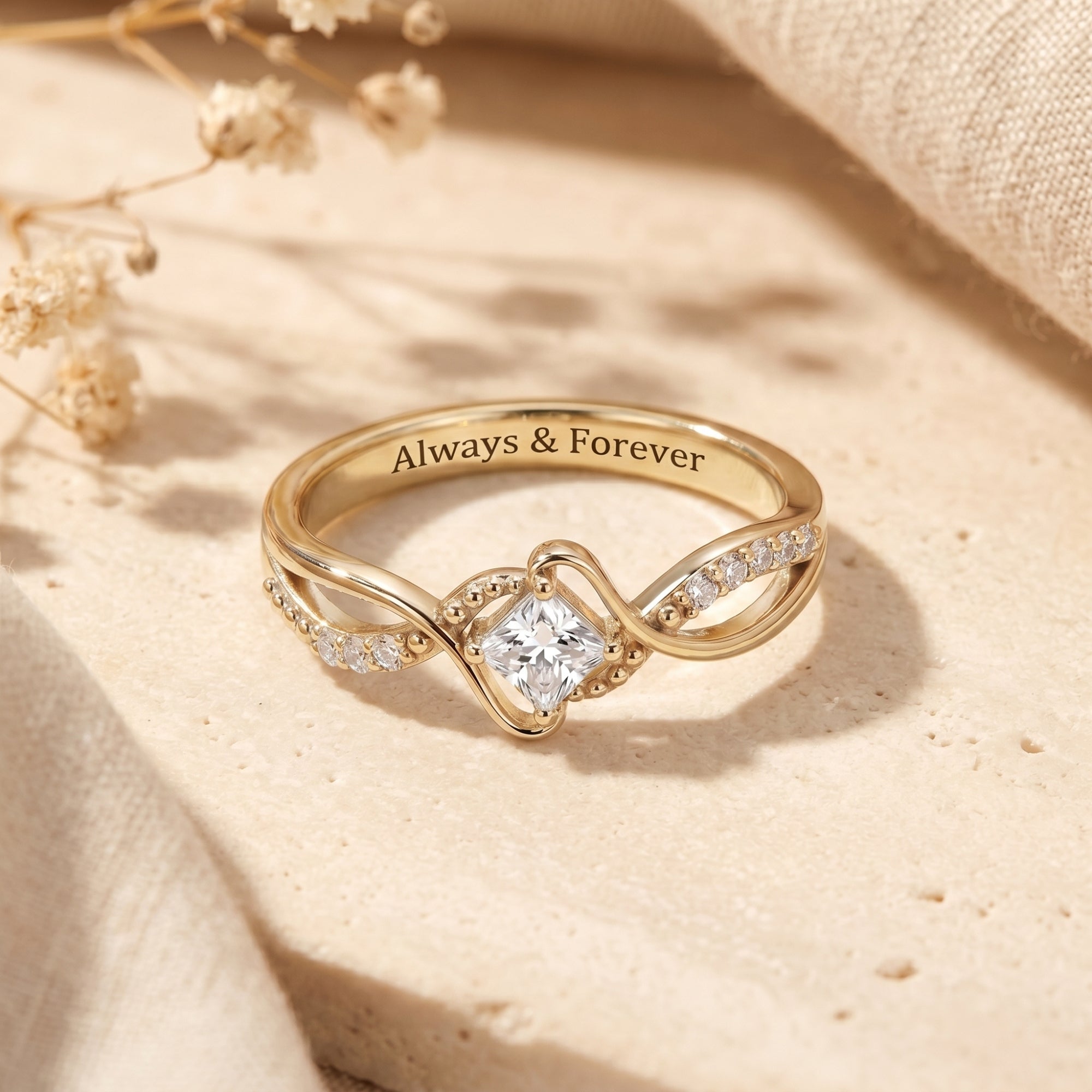 Gold princess cut moissanite promise ring with Always & Forever engraving on styled background.