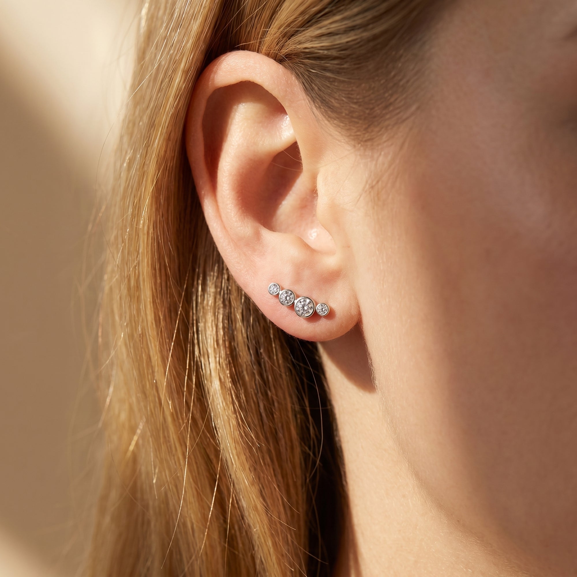 Silver moissanite climber earring with round-cut stones shown on a model's ear.