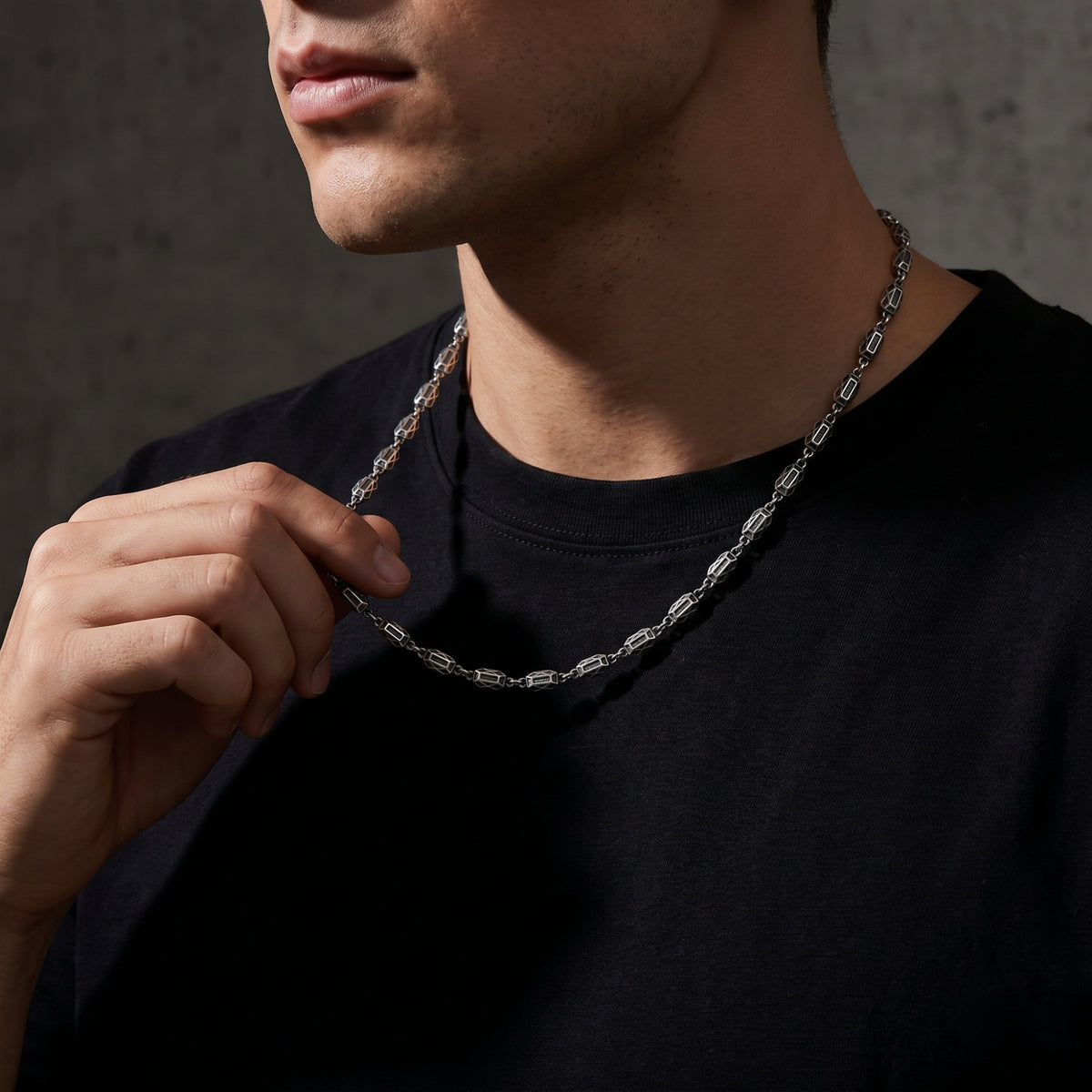 Man wearing the silver geometric link necklace over a black crewneck shirt.