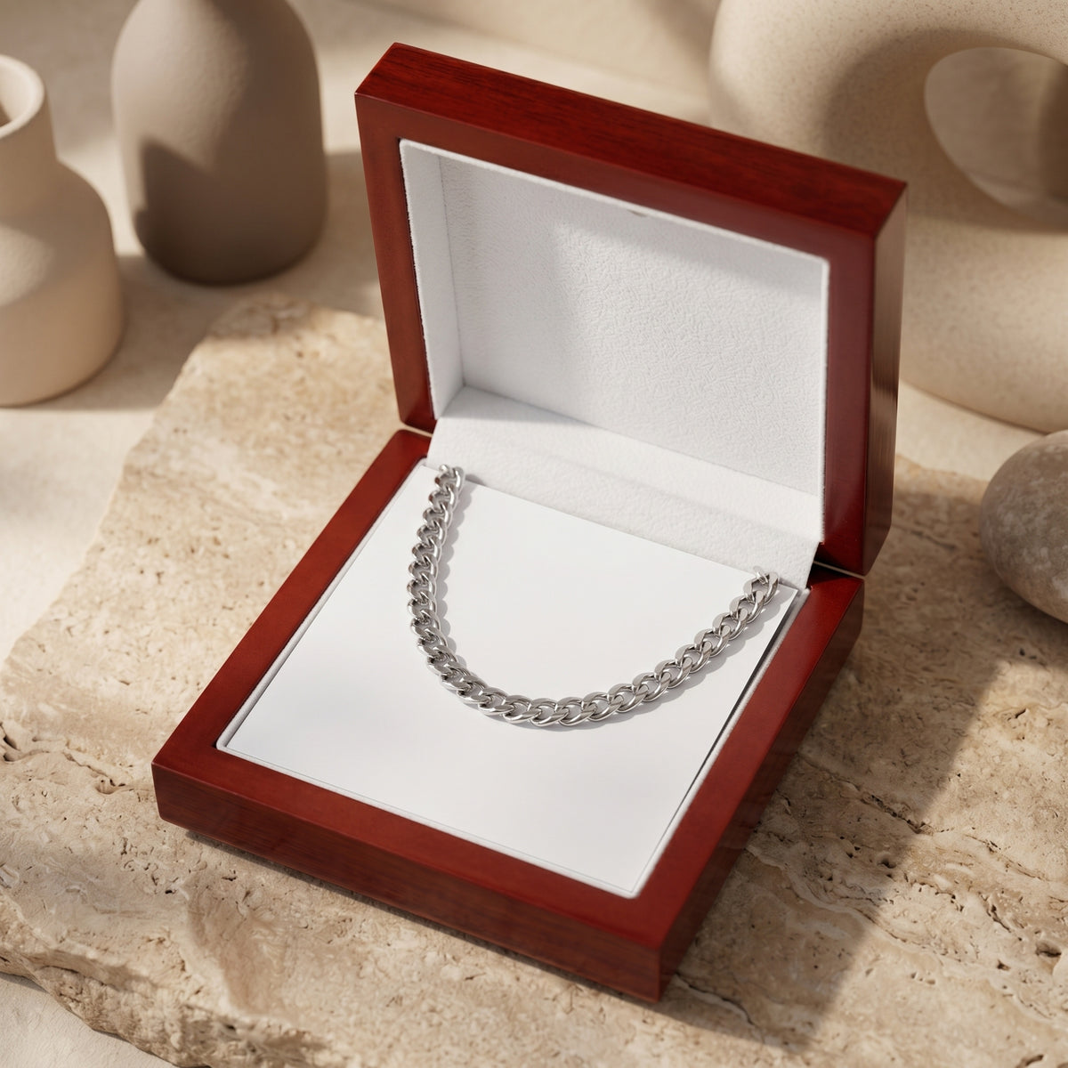 Silver Cuban link chain arranged on a blank card inside an open mahogany-style gift box.