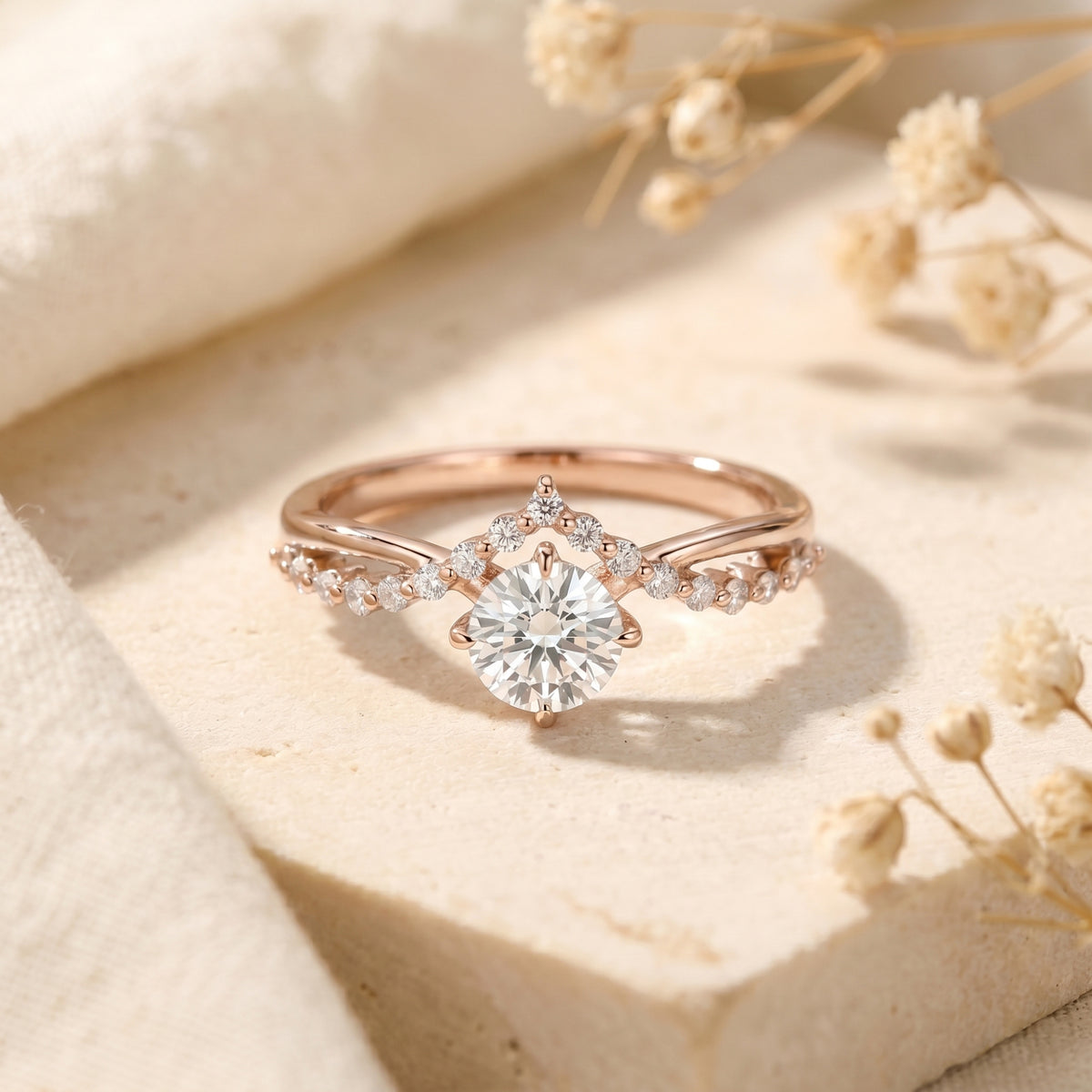 Rose gold Caladienne moissanite ring with a round-cut center stone and crown accent on a textured stone block.