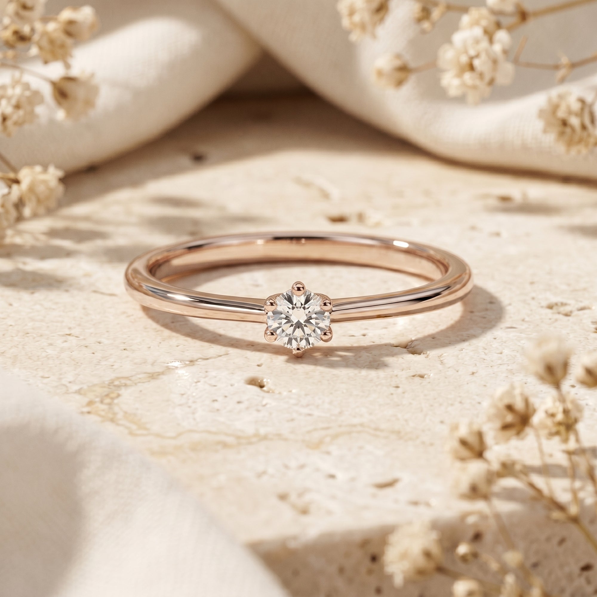 Rose gold round moissanite ring styled with dried flowers.
