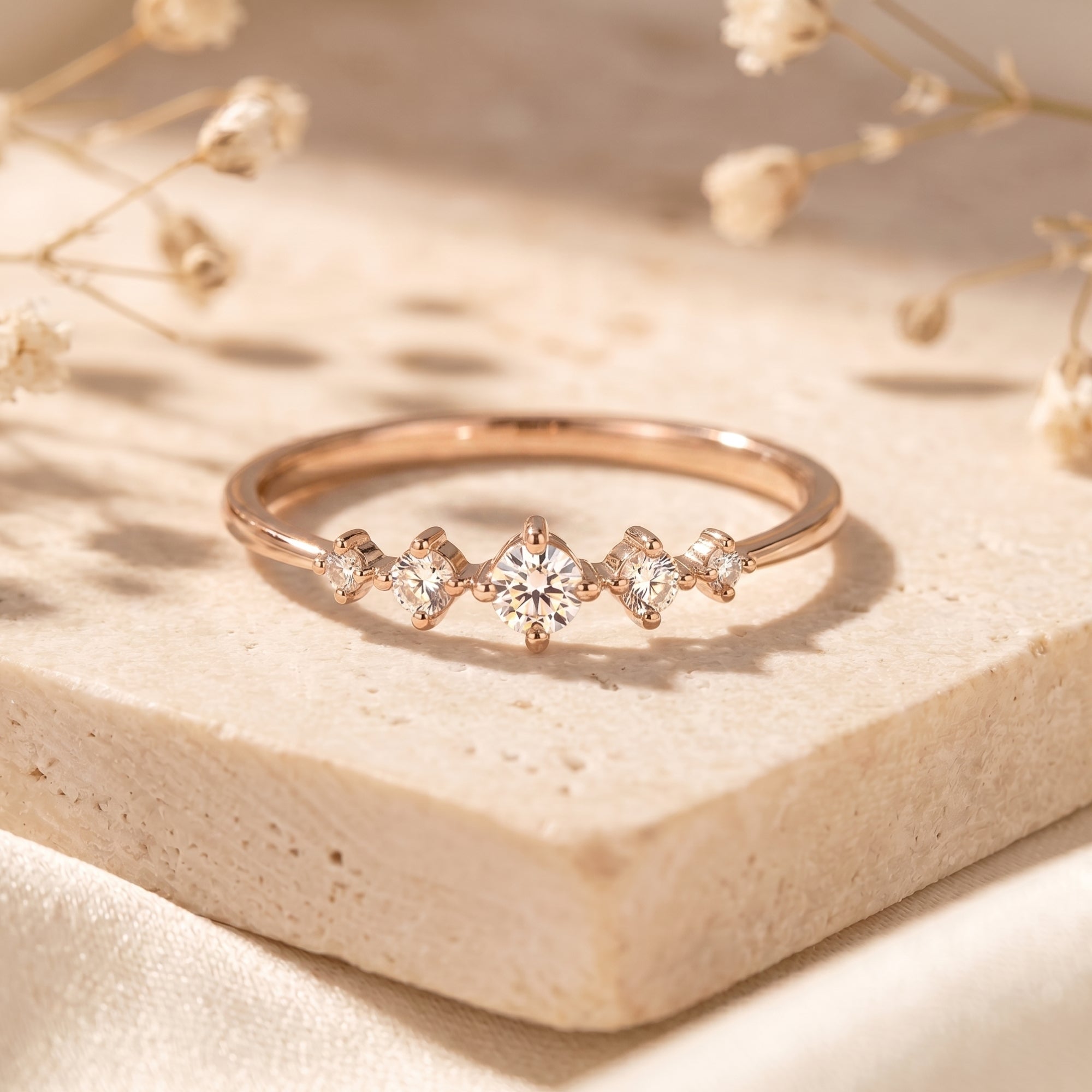 Rose gold moissanite ring with graduated stones in lifestyle setting.