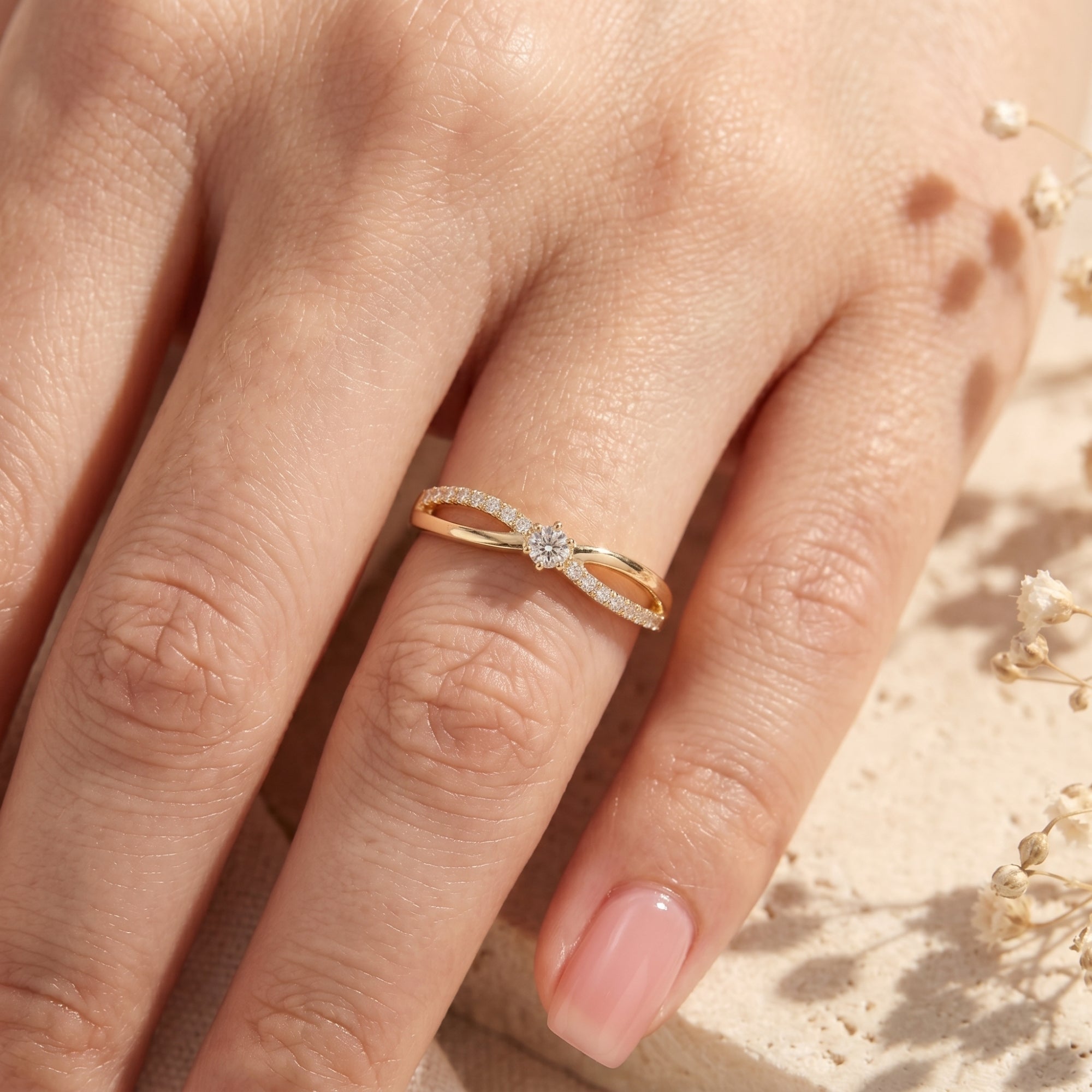 Top-down view of a gold moissanite bypass ring on a finger.