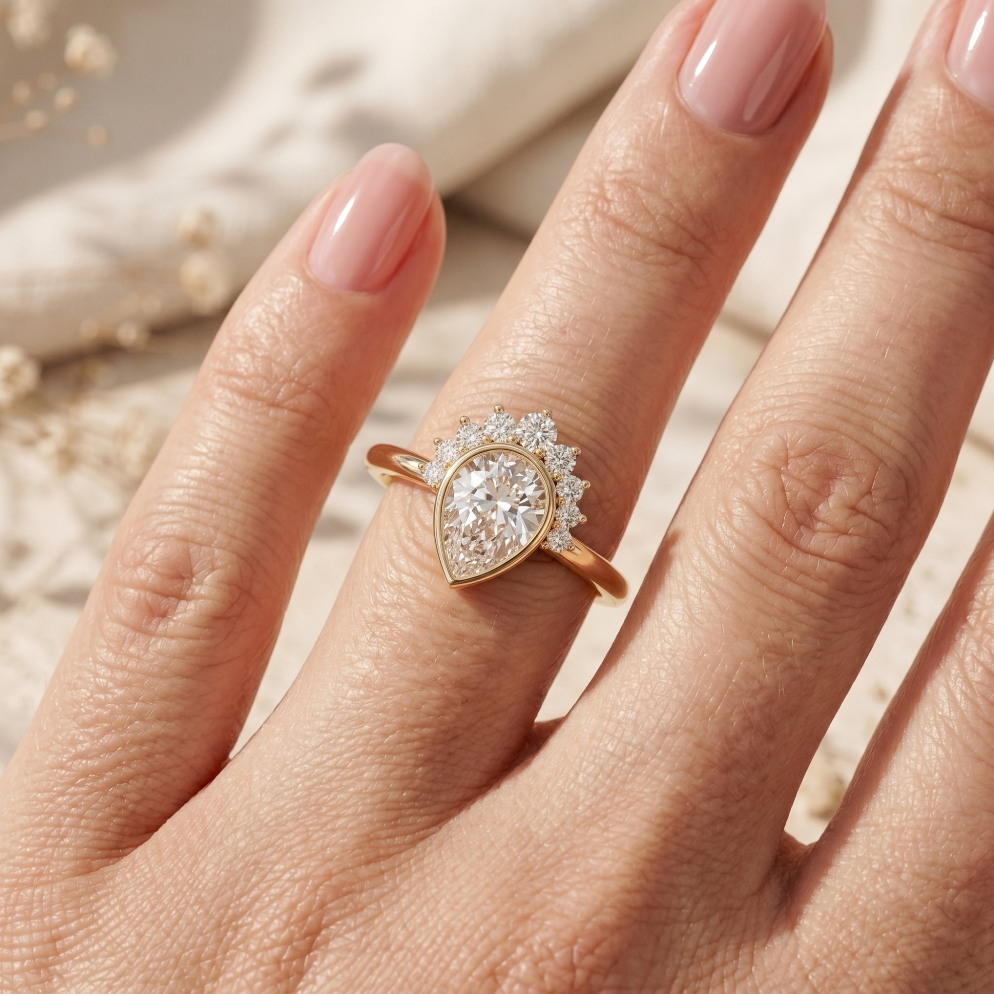Close-up of a gold pear-cut moissanite promise ring worn on a hand.