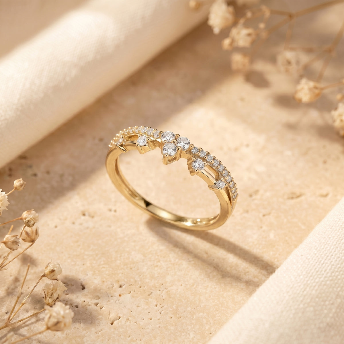 Yellow gold Ismerelle crown-inspired ring with round simulated diamonds on a textured stone surface.