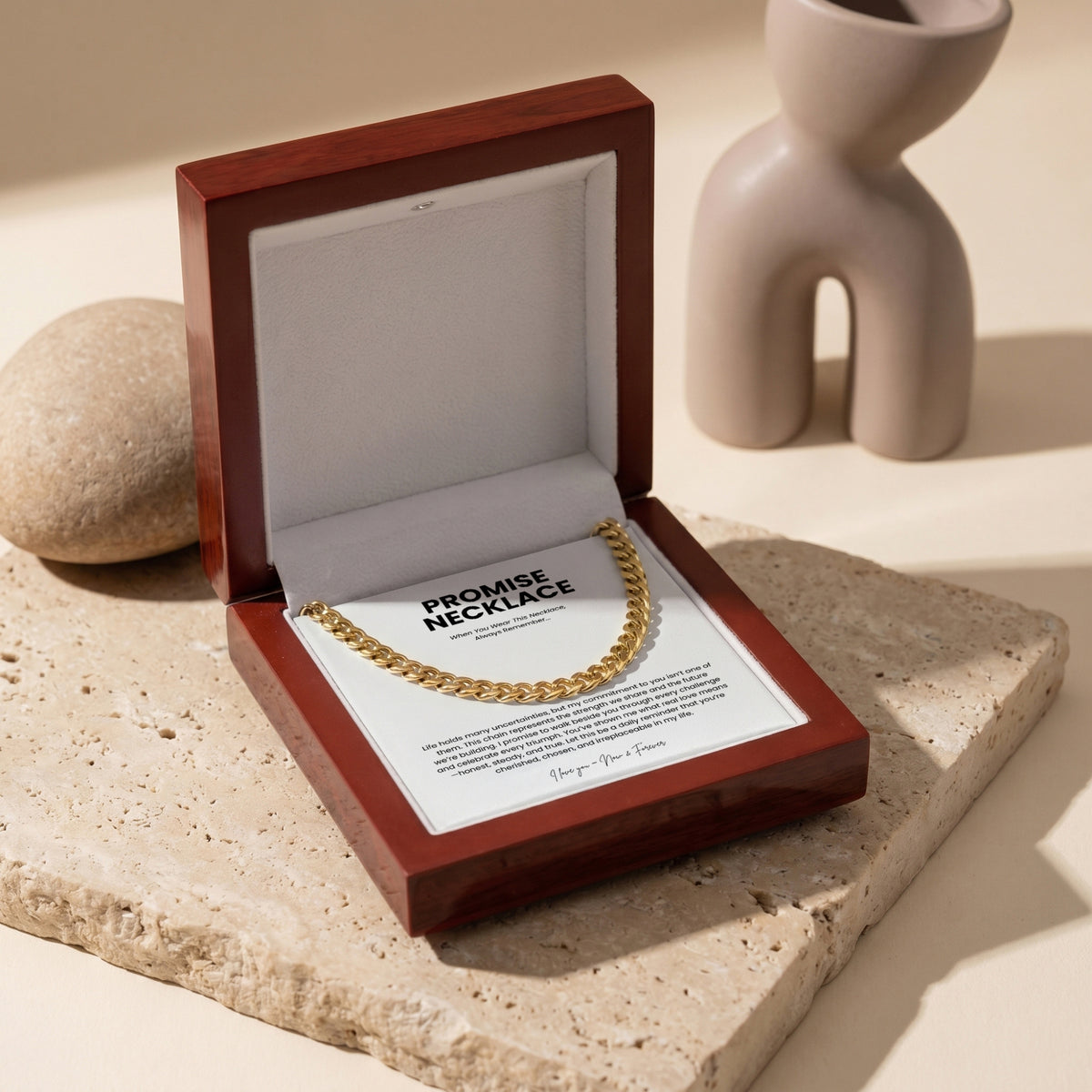 Gold-tone Cuban link chain arranged on a printed message card inside an open wooden display box.
