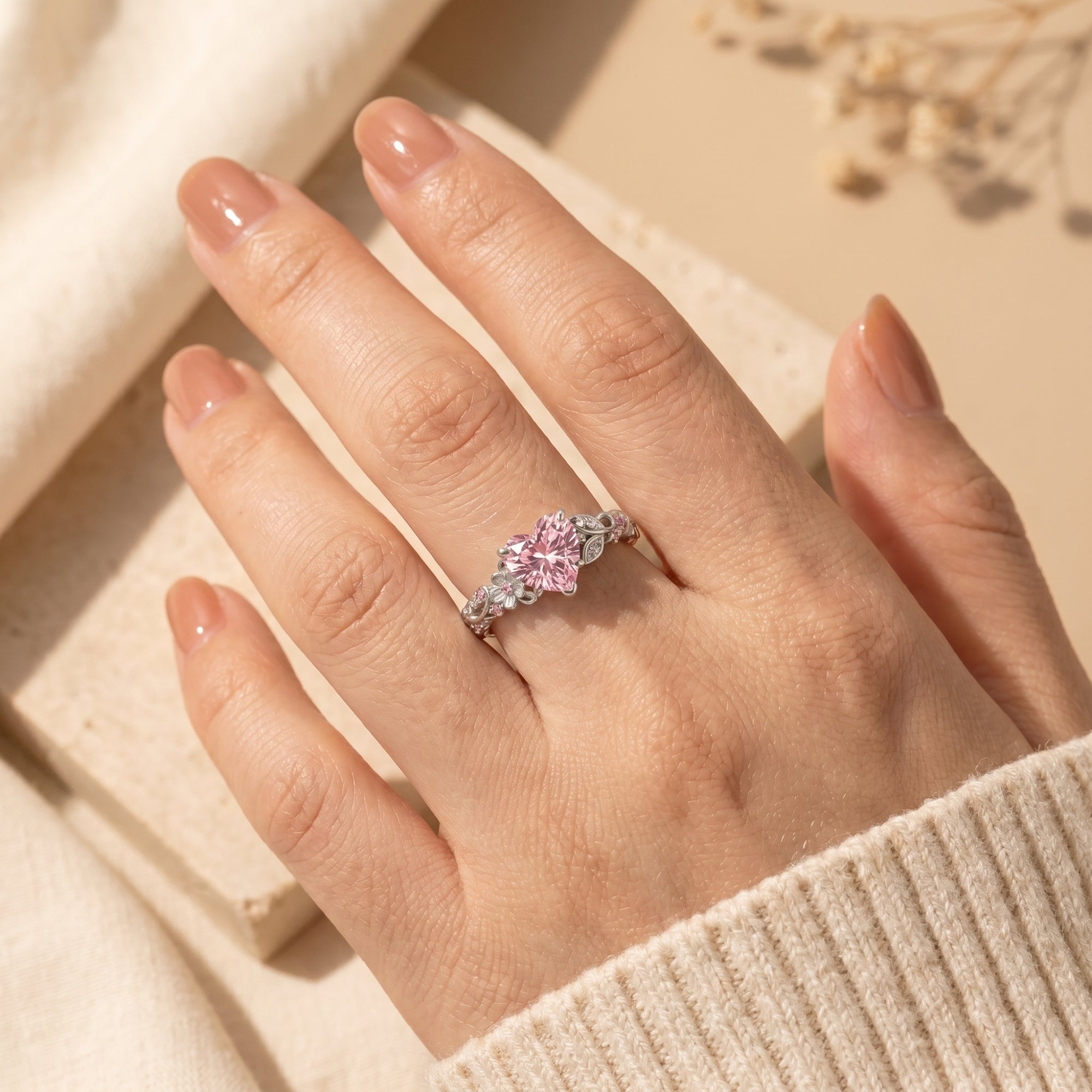 Silver heart-cut pink diamond ring on finger for scale.