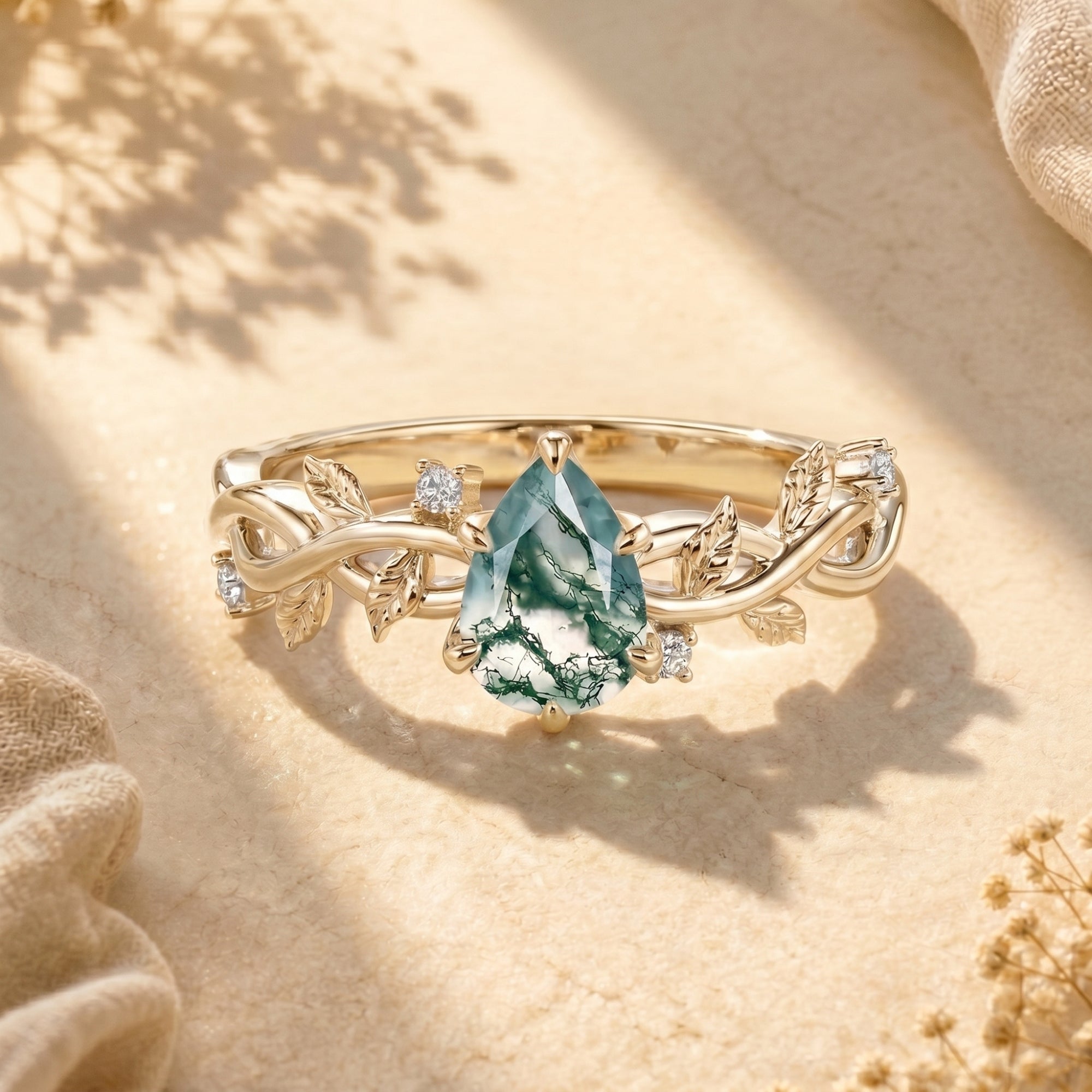 Yellow gold pear-cut moss agate ring with decorative vine band.