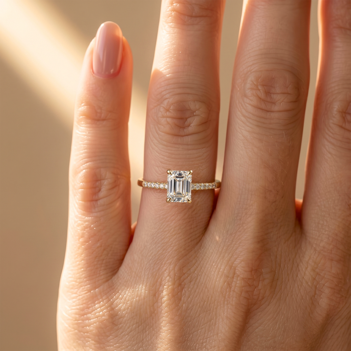 Close-up of a yellow gold emerald cut moissanite engagement ring showcased on a model's hand.