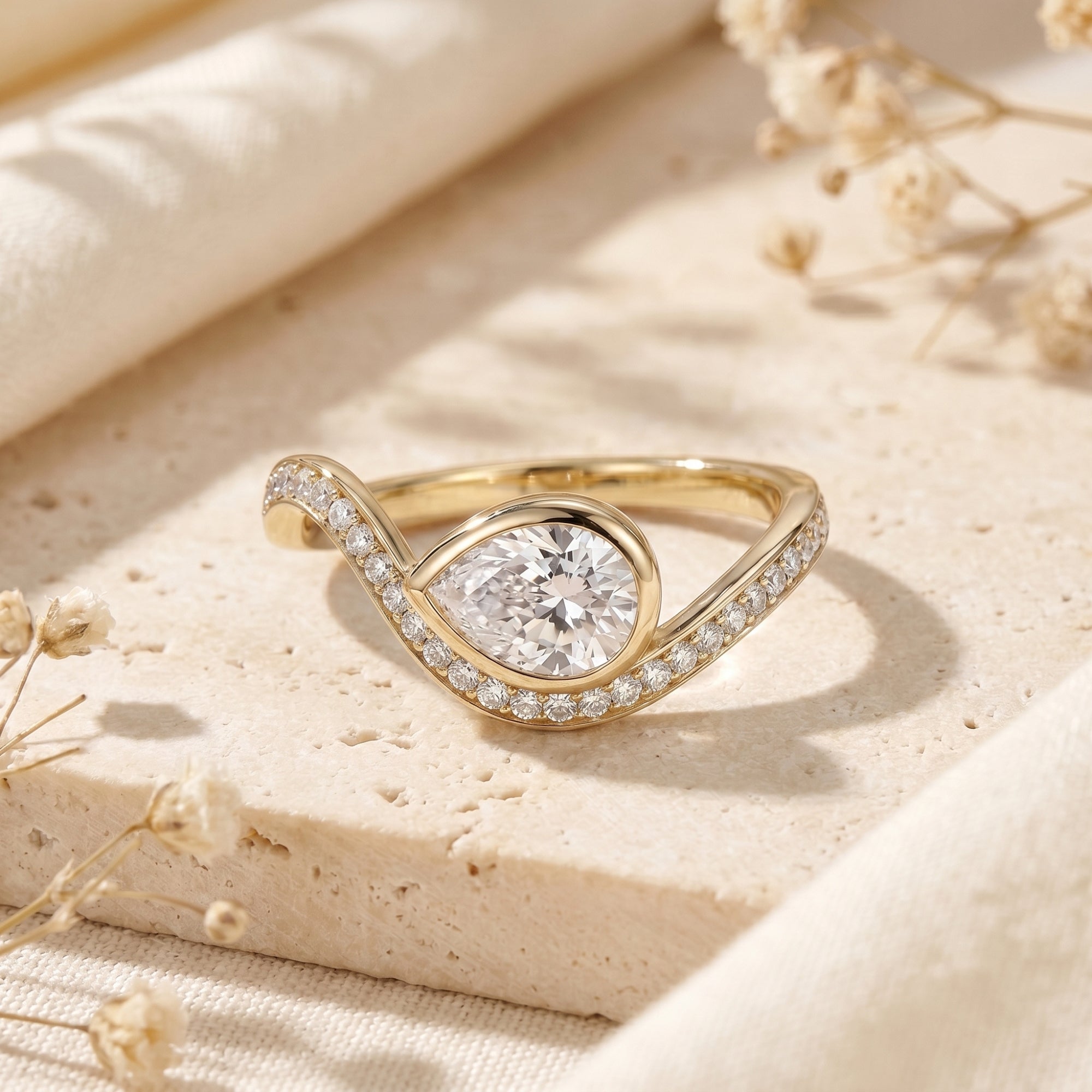 Yellow gold pear-cut moissanite bypass ring with floral accents.