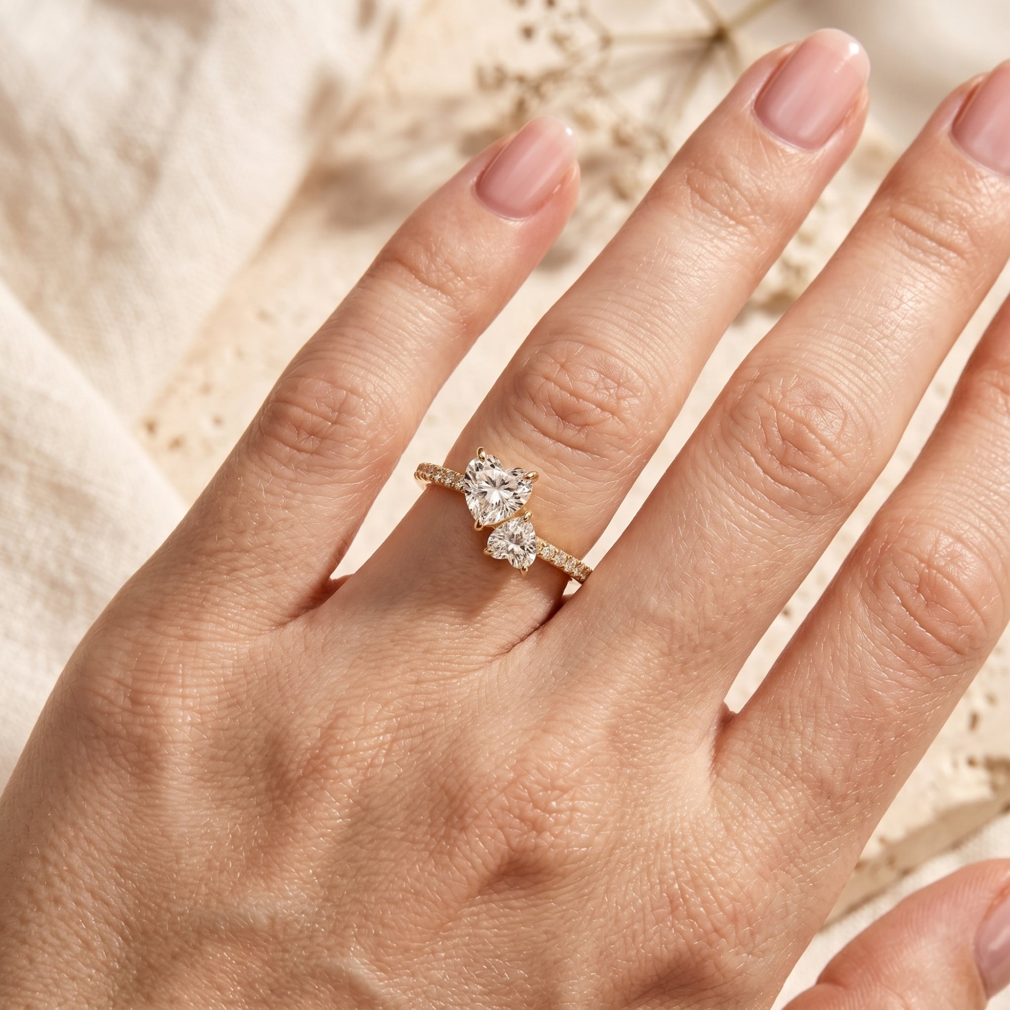 Gold-plated moissanite promise ring on a finger showing the scale of the heart-cut stones.