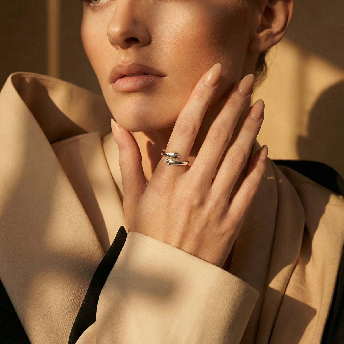 Model wearing the silver-tone hug ring on her middle finger in warm sunlight.