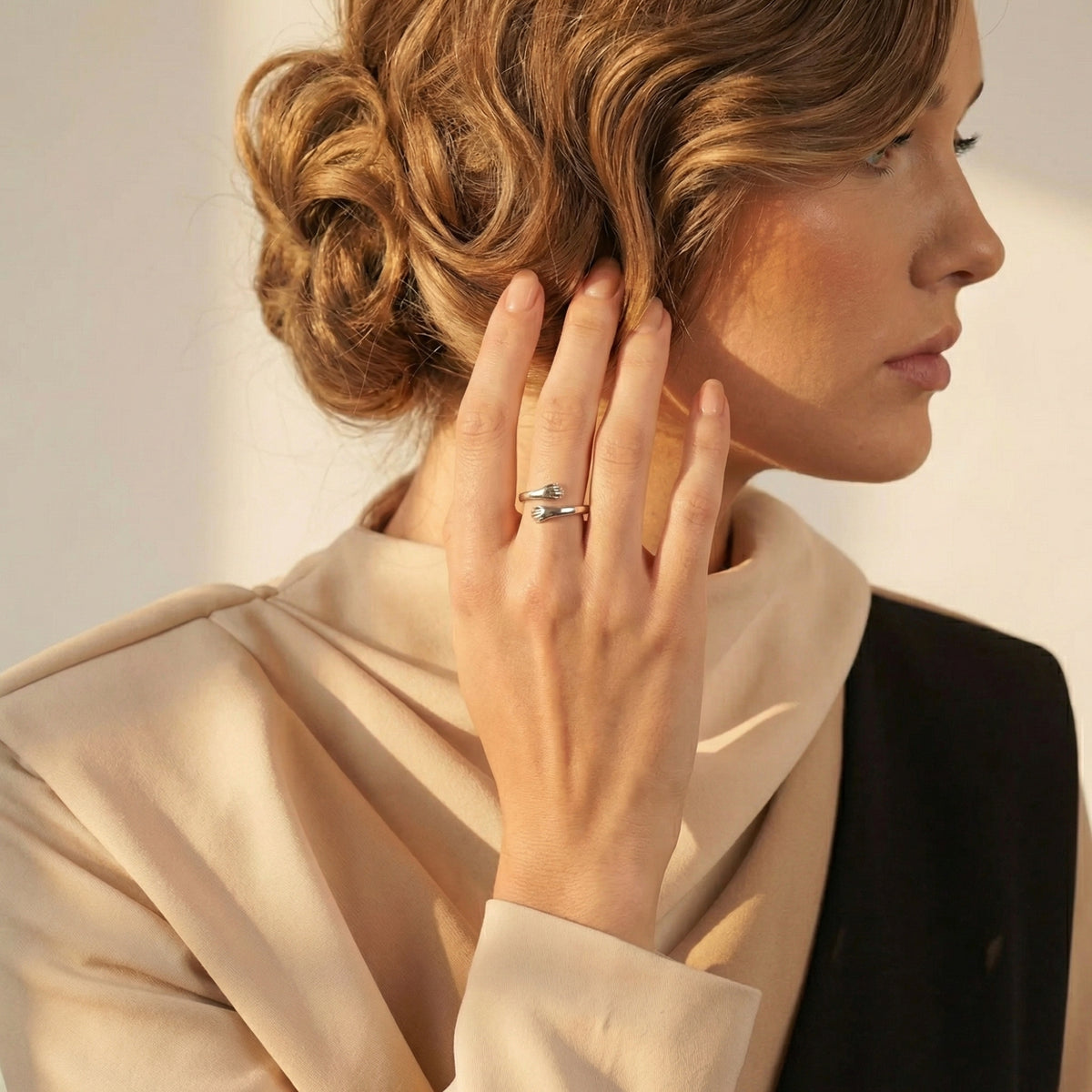 Silver hug ring styled on a model in profile, with her hand resting near her hair.